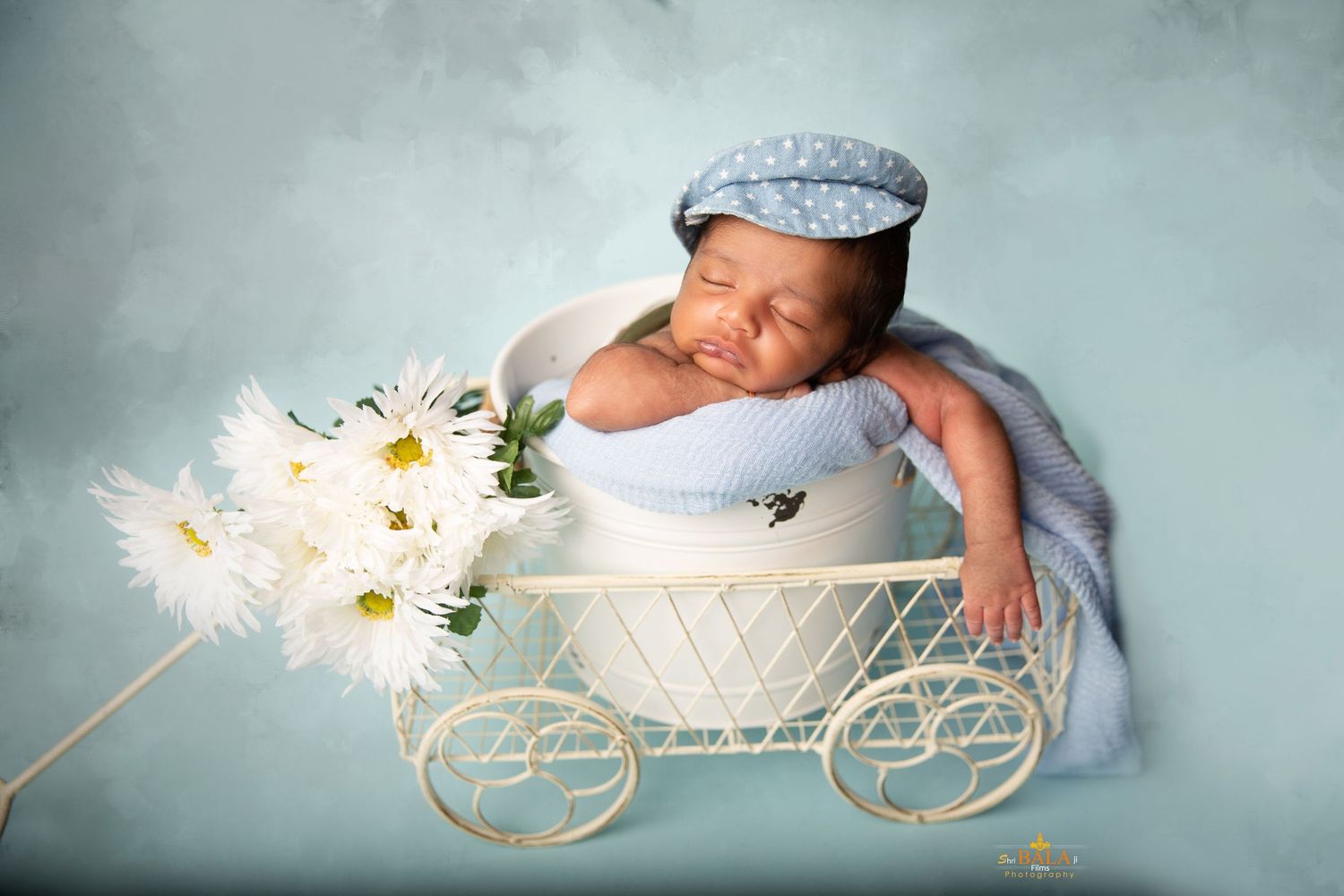 Newborn baby sleeping peacefully in soft blue blankets with twinkling sparklers creating a magical atmosphere.