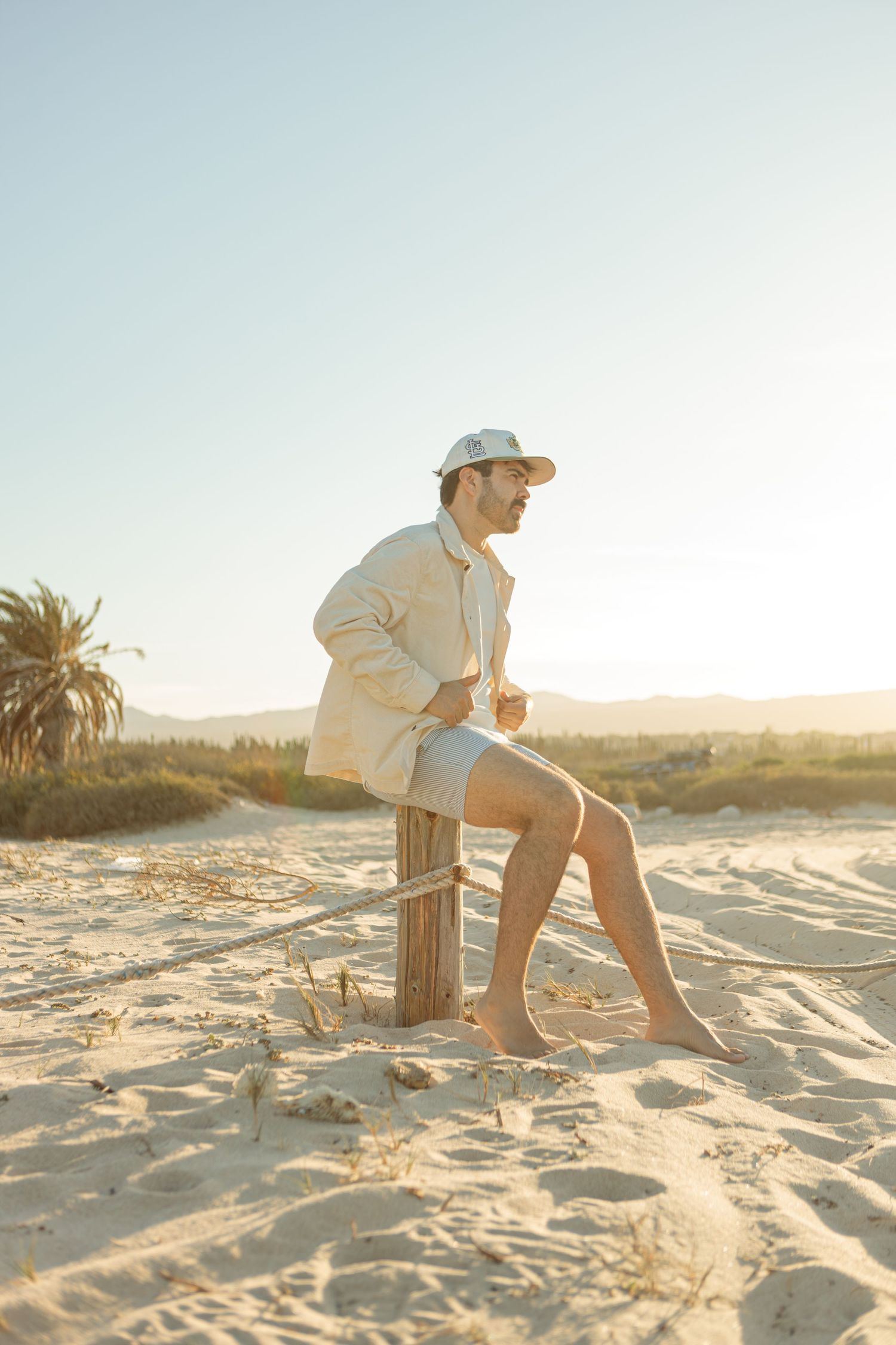 Solo beach portrait of a man at golden hour in Los Cabos, wearing neutral tones and surrounded by sand dunes in the Baja Sur
