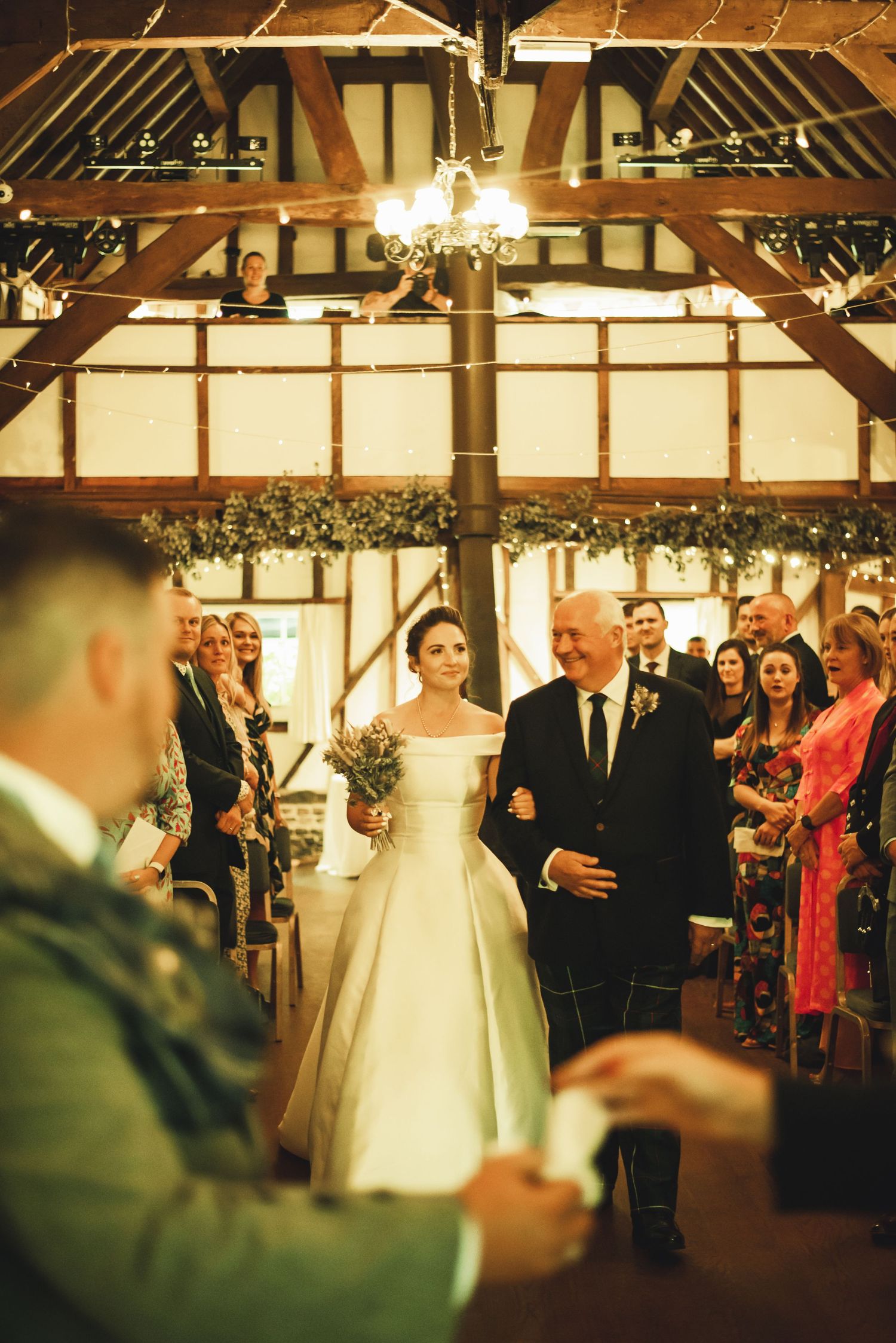 Kent wedding.A series of candid wedding reception moments in a rustic barn venue decorated with twinkling lights and exposed beams.