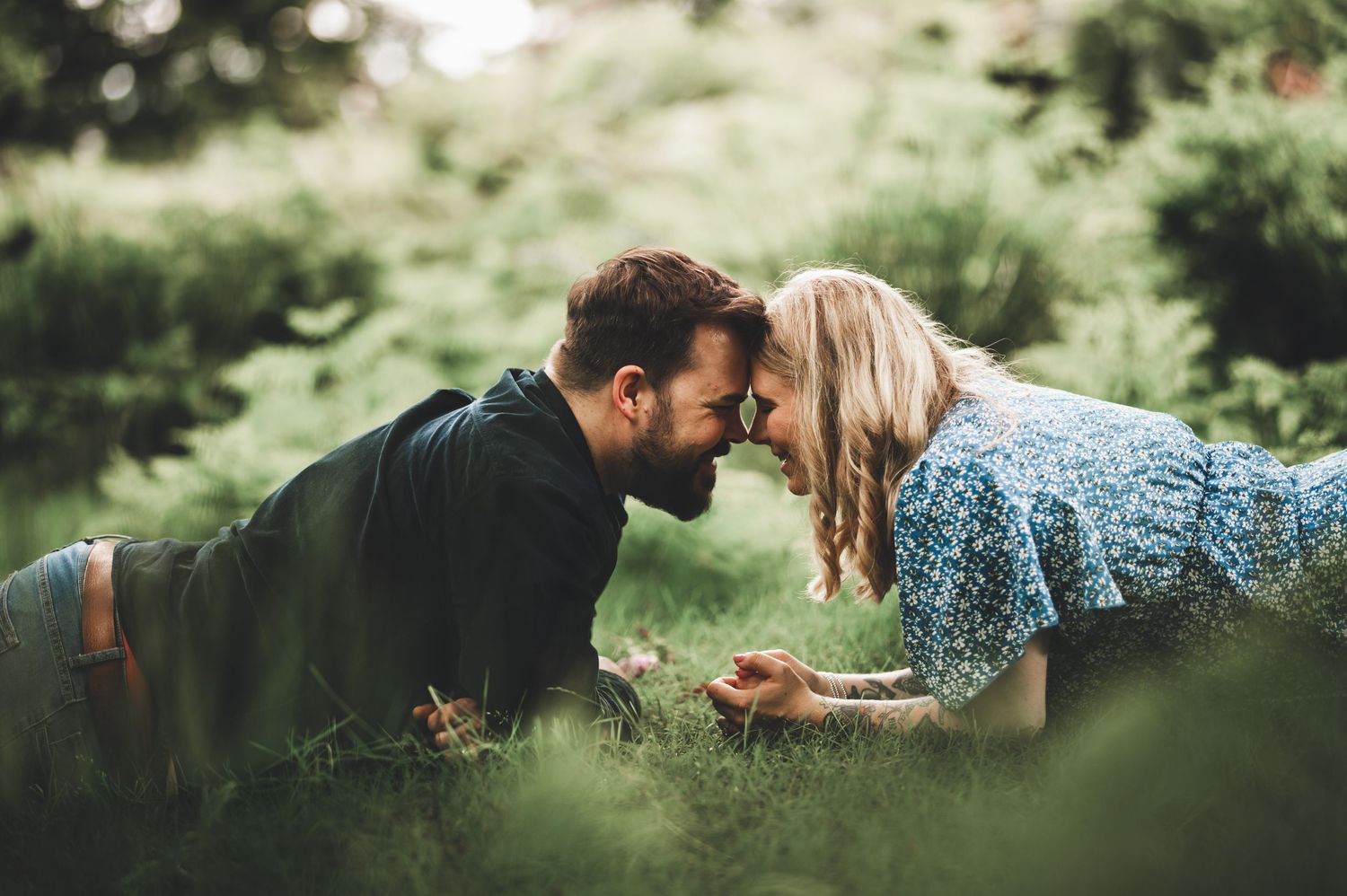 Romantic couple lying in grass during outdoor photo session.