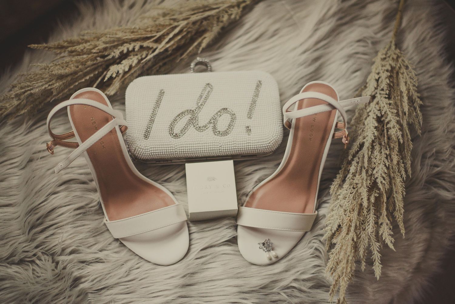Wedding shoes and 'I do' sign styled with dried wheat on furry background.
