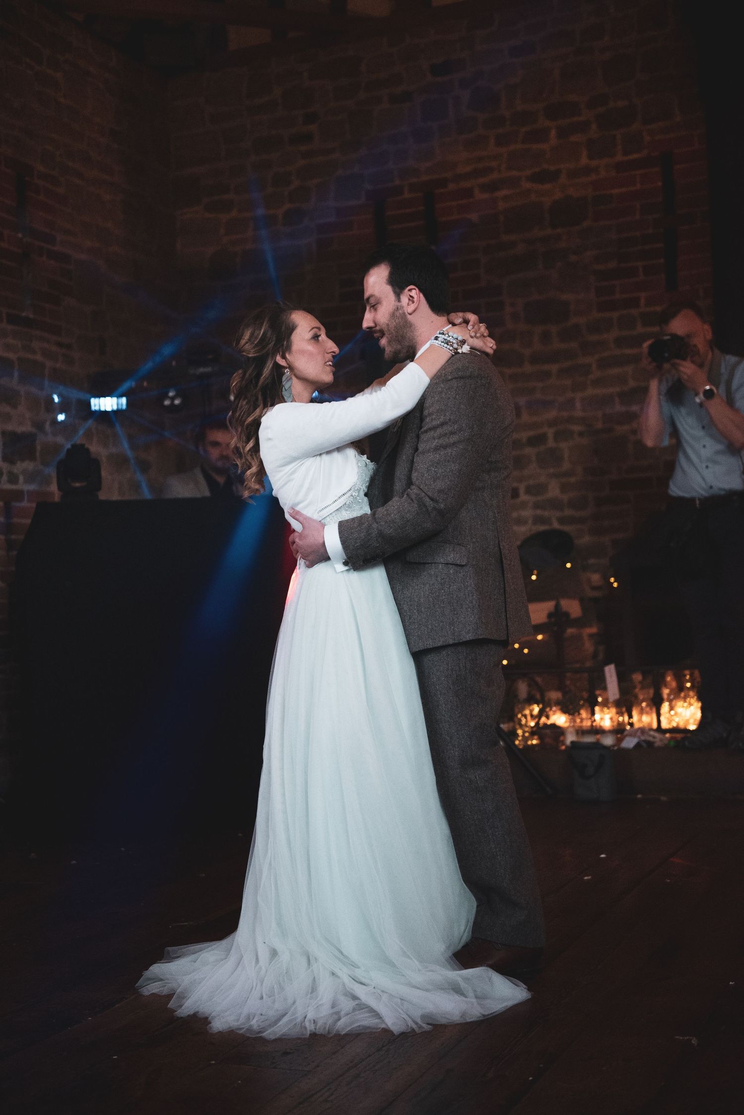 Romantic first dance at wedding reception with candlelit brick wall backdrop.