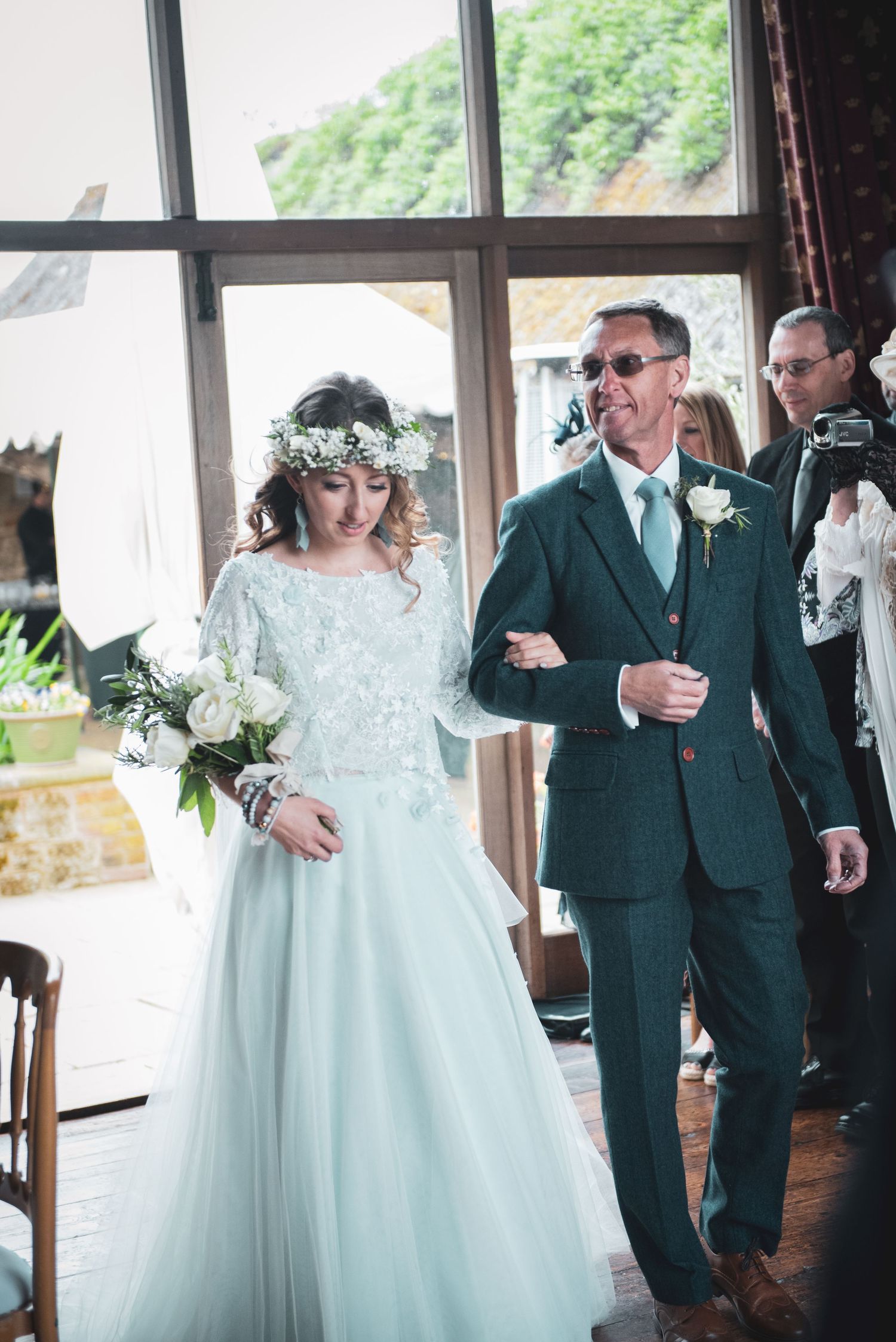 A beautiful rustic wedding ceremony with the bride in a lace gown and groom in a dark green suit.