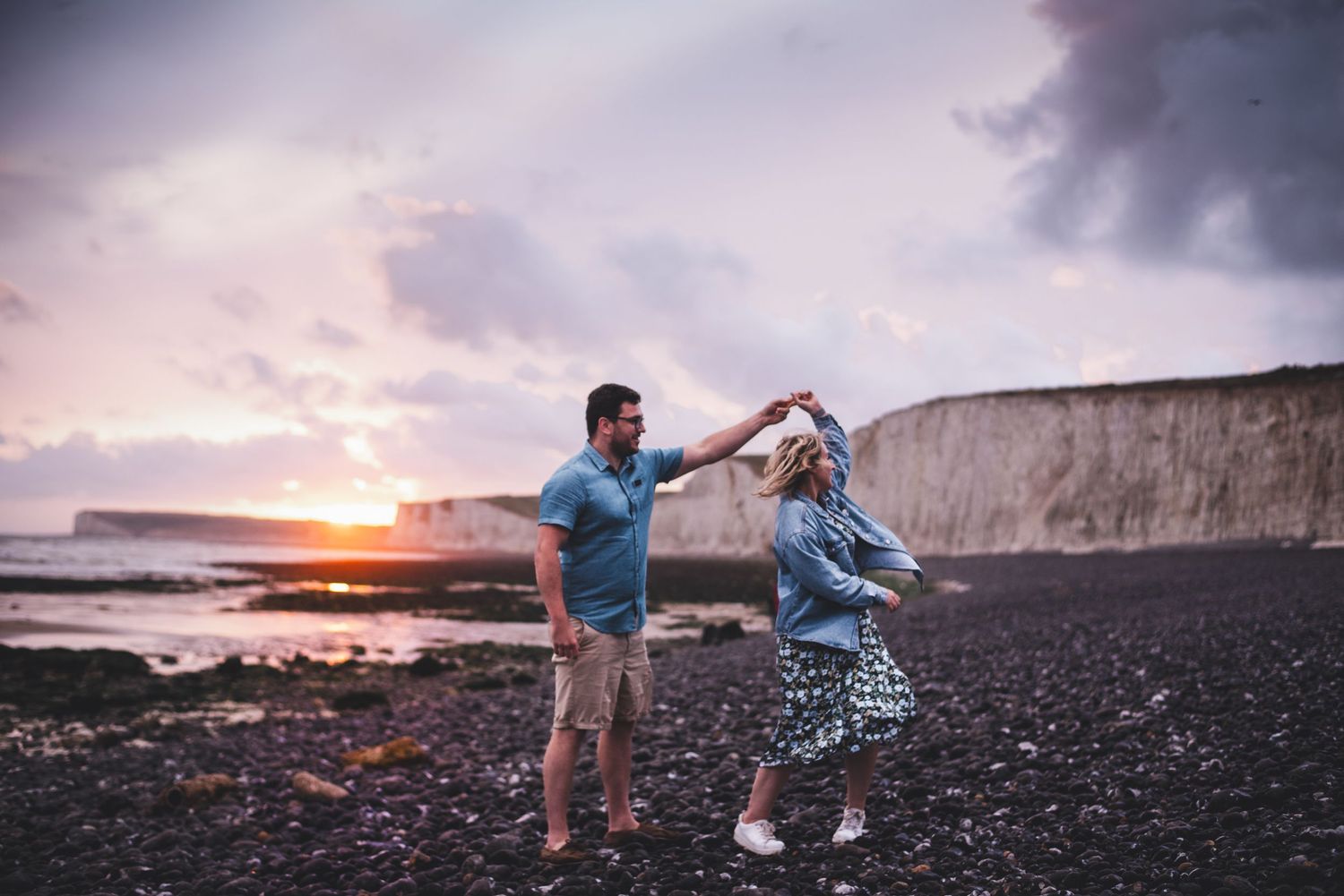 Surrey Engagement shoot beach photography session with dramatic cliffs and sunset in the background.