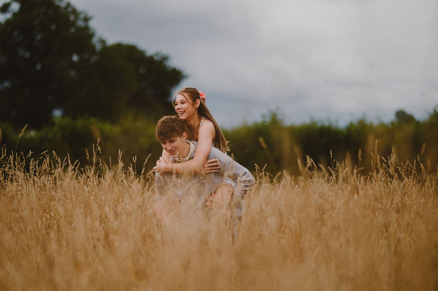 Two people sit in a golden wheat field during sunset with warm evening light creating a peaceful summer atmosphere.