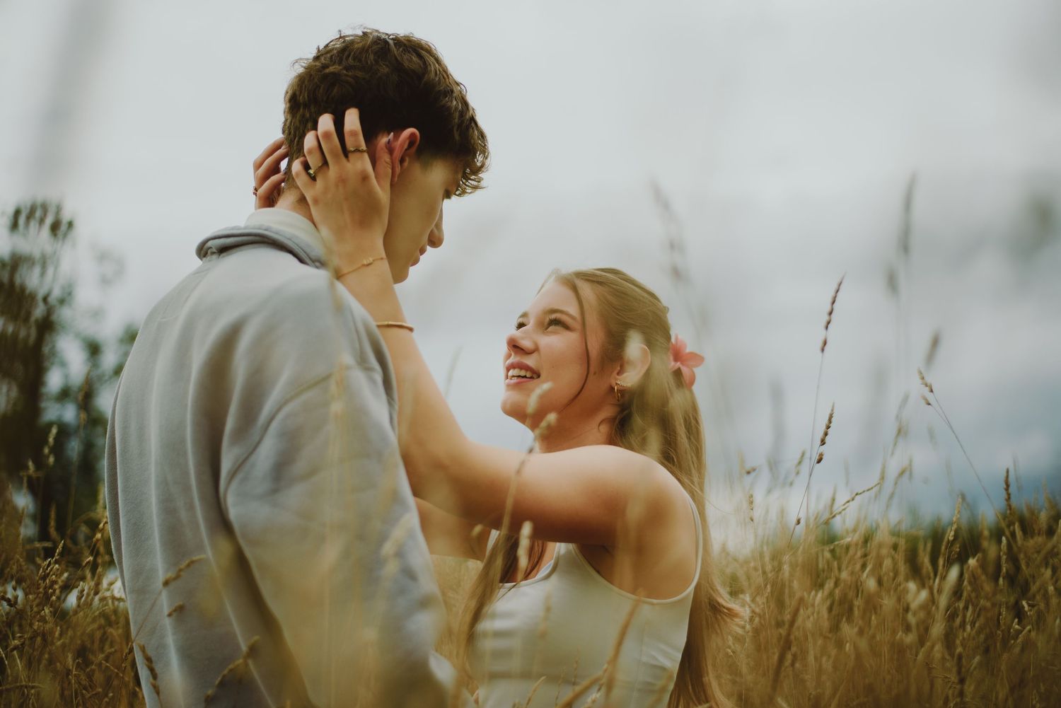 A couple shares intimate moments together in a golden wheat field at sunset.