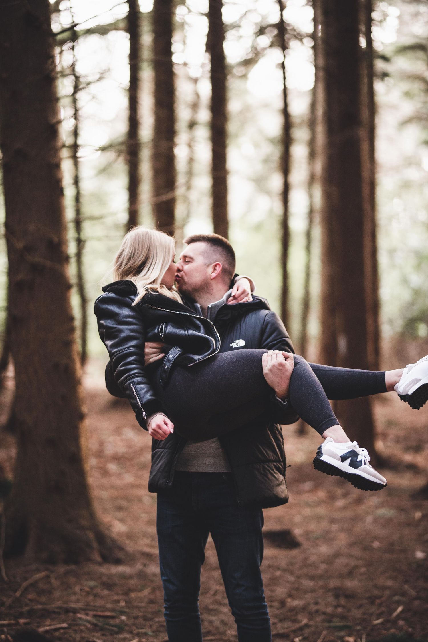 Kent engagement shoot. sharing a playful moment in a pine forest setting.