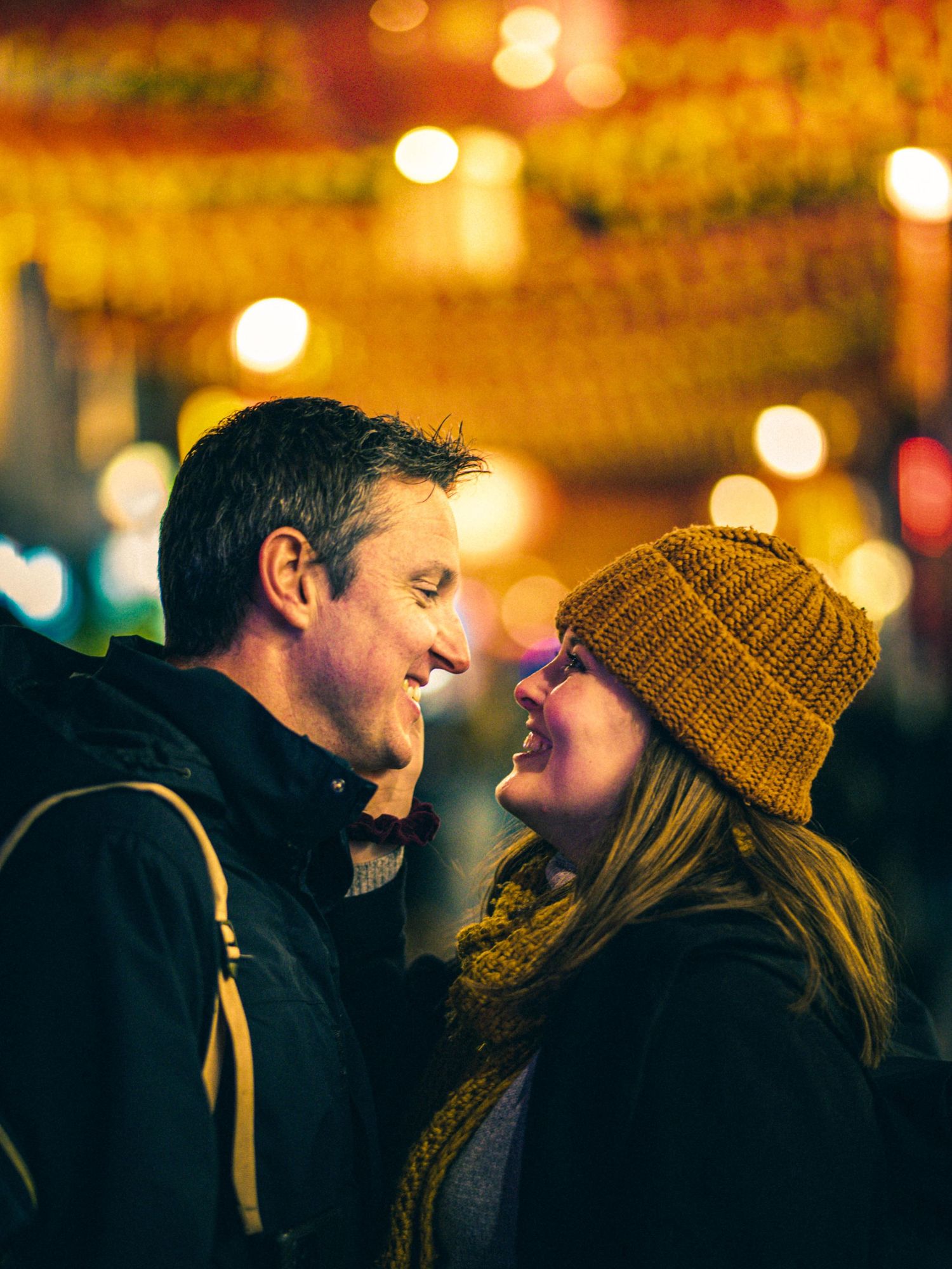 A couple sharing an intimate moment at night under warm glowing lights.