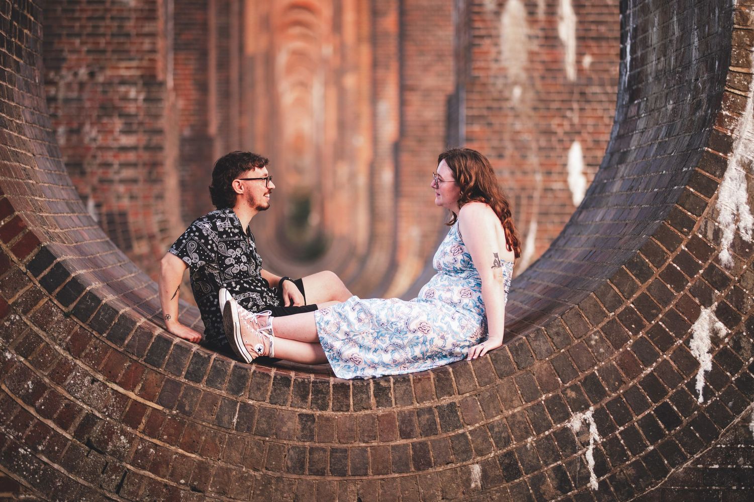 Kent engagement shoot. posing through circular brick archways in historical architecture.
