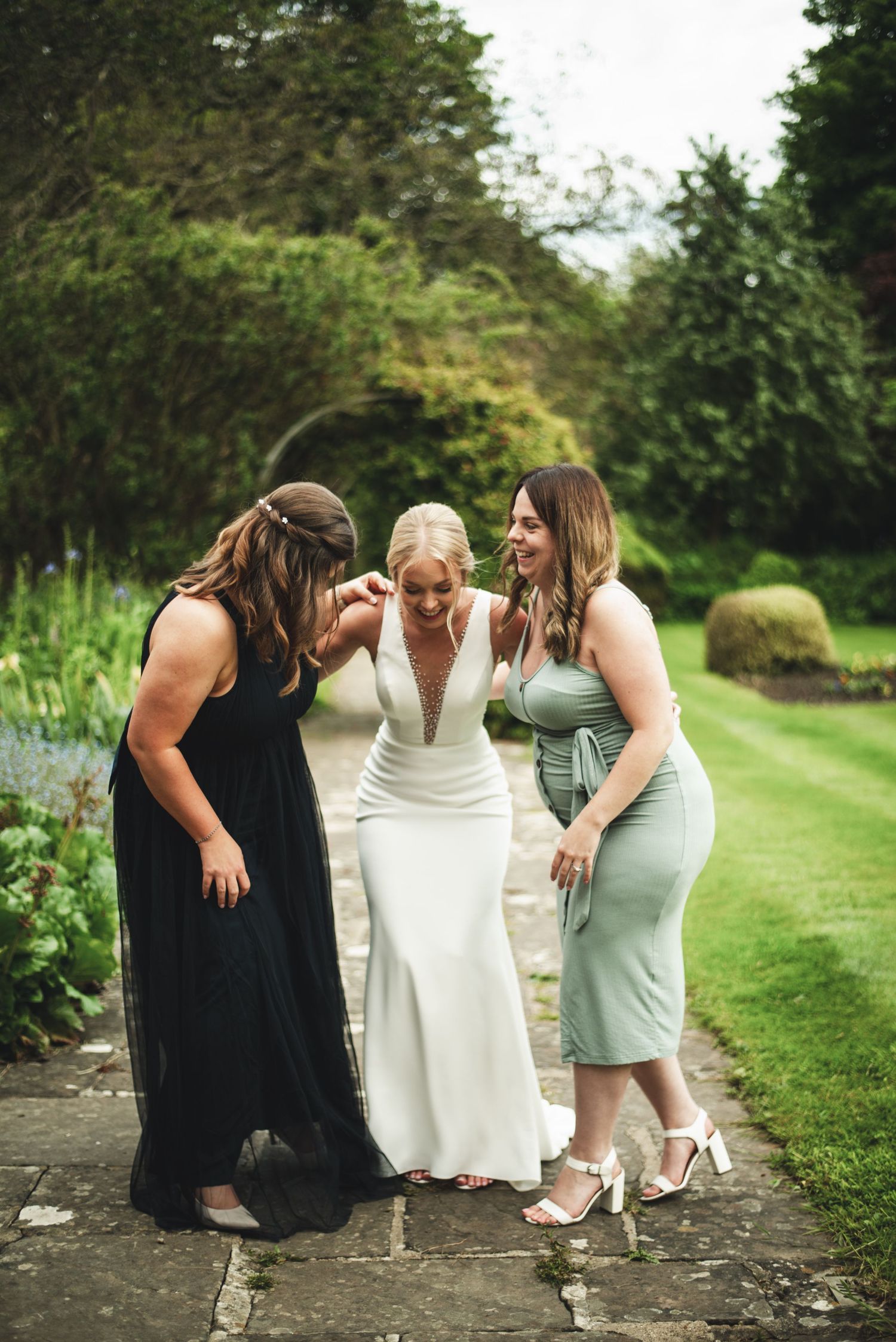 Three friends sharing a candid moment together while sitting on garden steps.