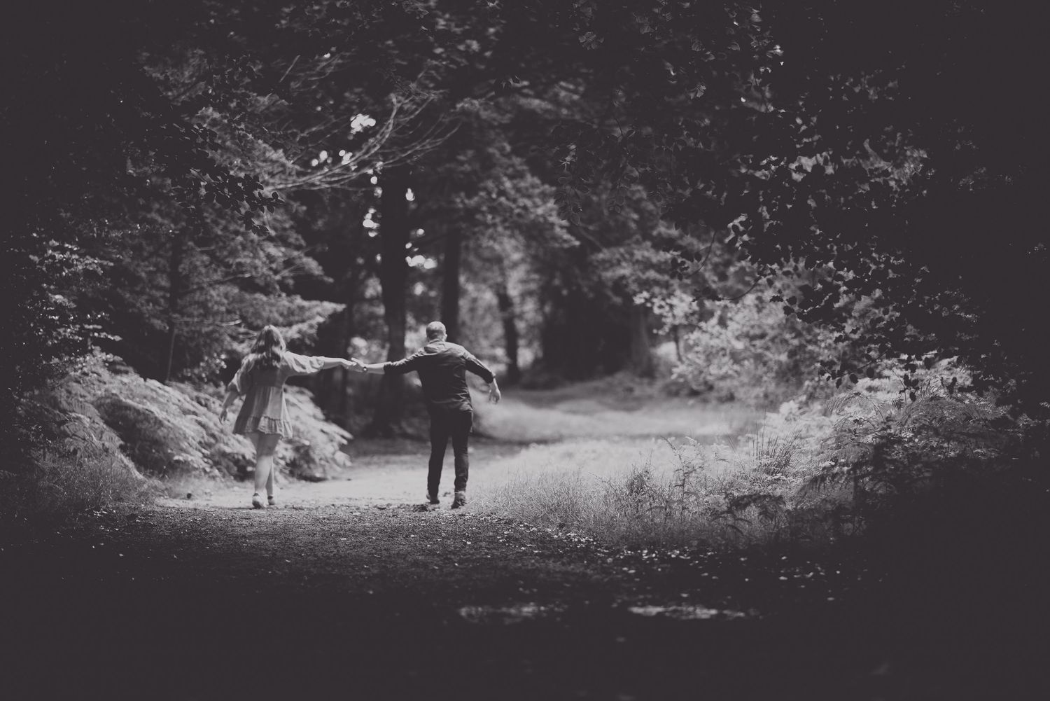 East Sussex engagement shoot. silhouettes of people walking through a misty forest path at dusk.