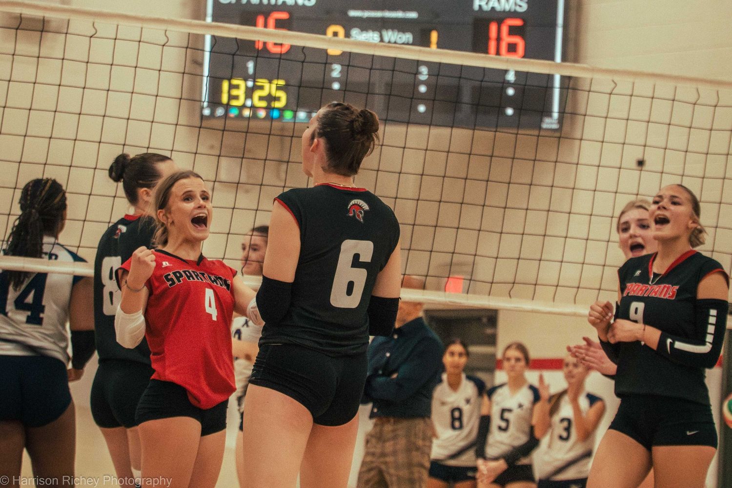 Players celebrate a point during a competitive volleyball match with team celebrations.