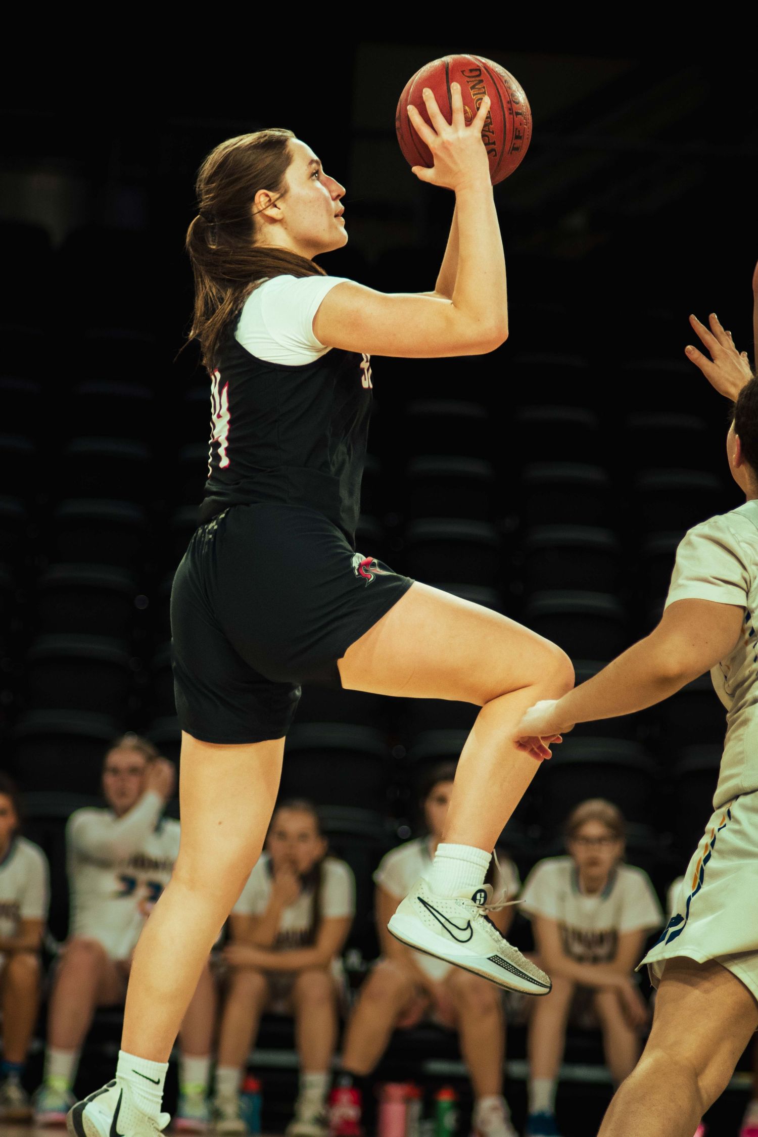 Basketball player leaps high to make a shot during an indoor game.