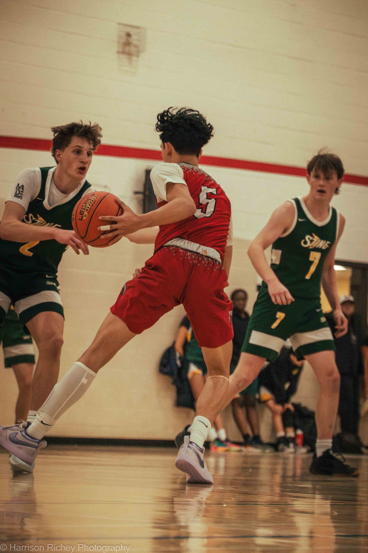 Young basketball players leap and collide while competing for possession on the court.