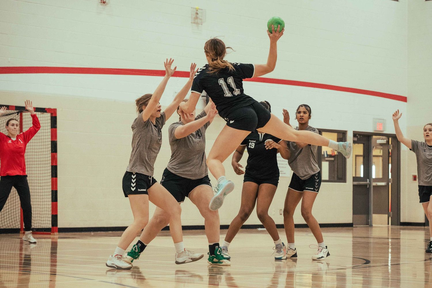 Athletes practicing volleyball skills in an indoor gymnasium.