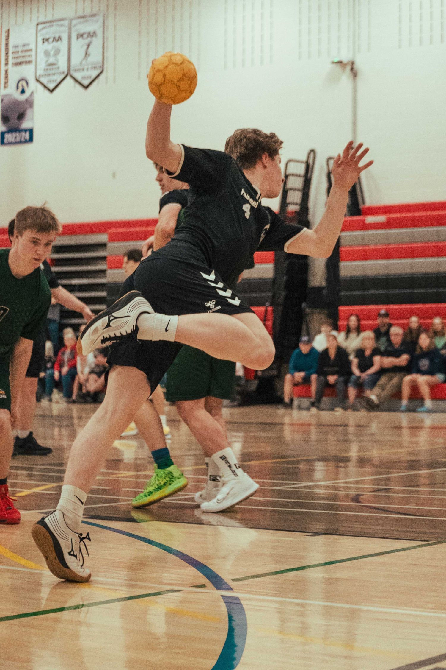 Basketball players in black uniforms perform drills during practice session.