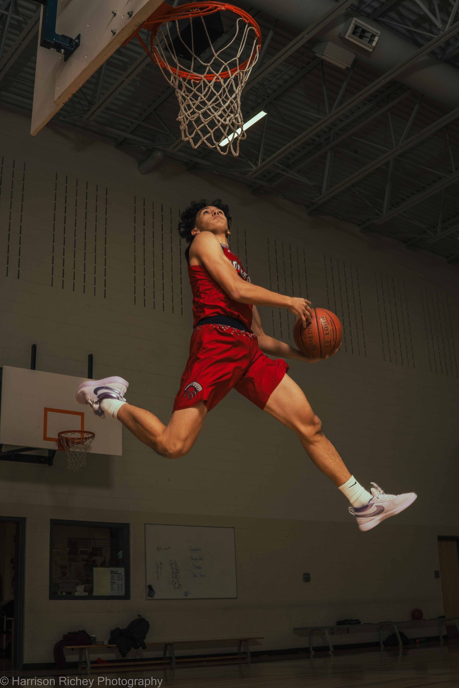 Sequence shows basketball player performing dynamic dunk in red uniform against dark background.
