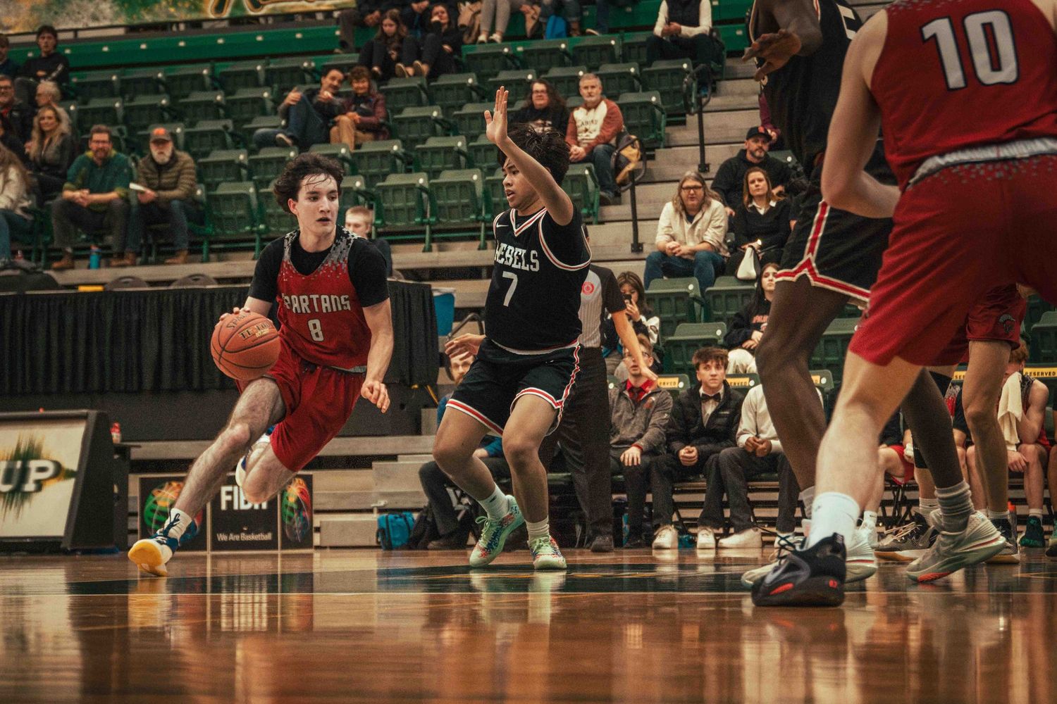 Basketball player dribbles around defender during intense game play.