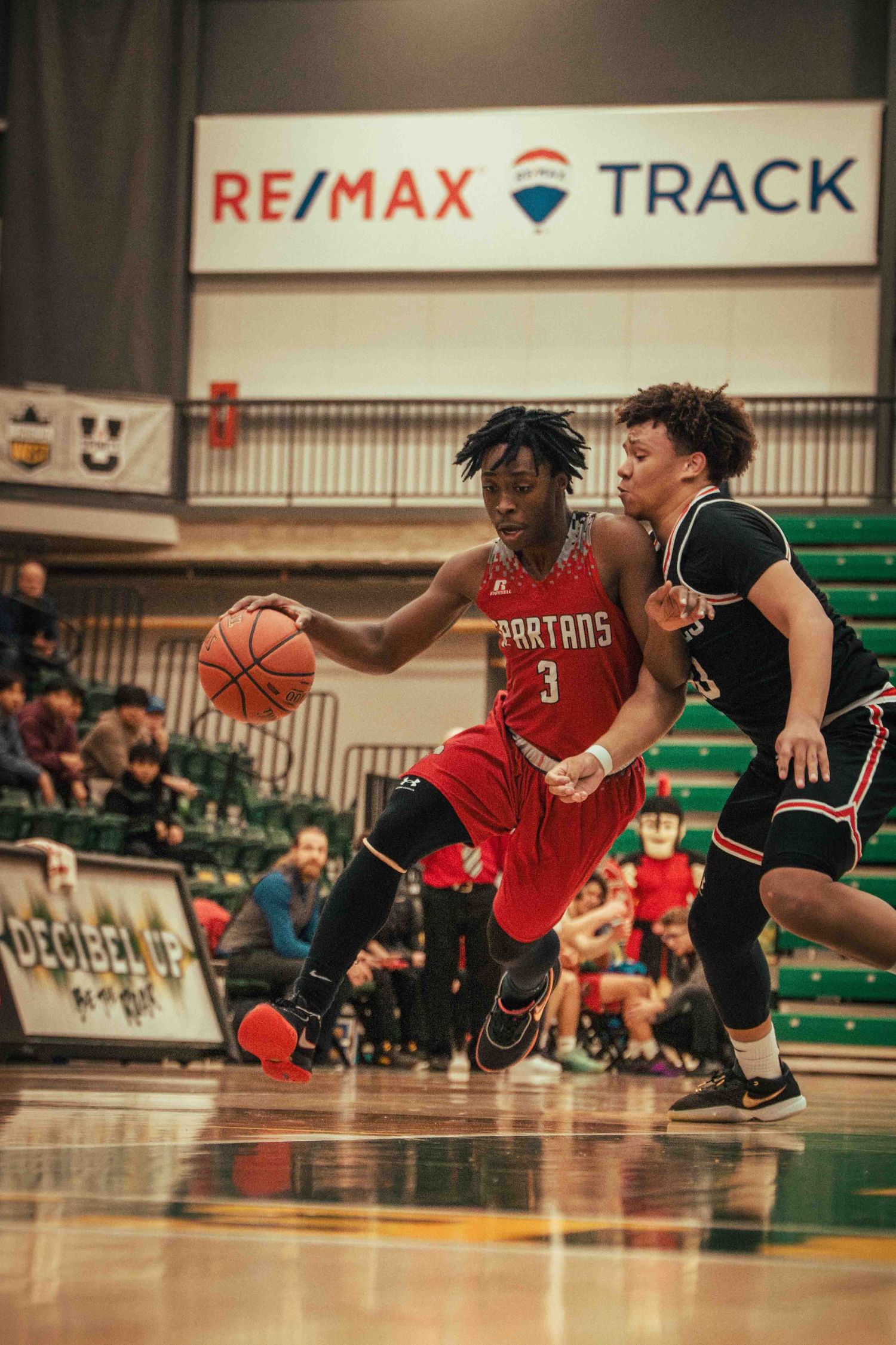 Basketball player in red jersey dribbling past defender during intense game action.