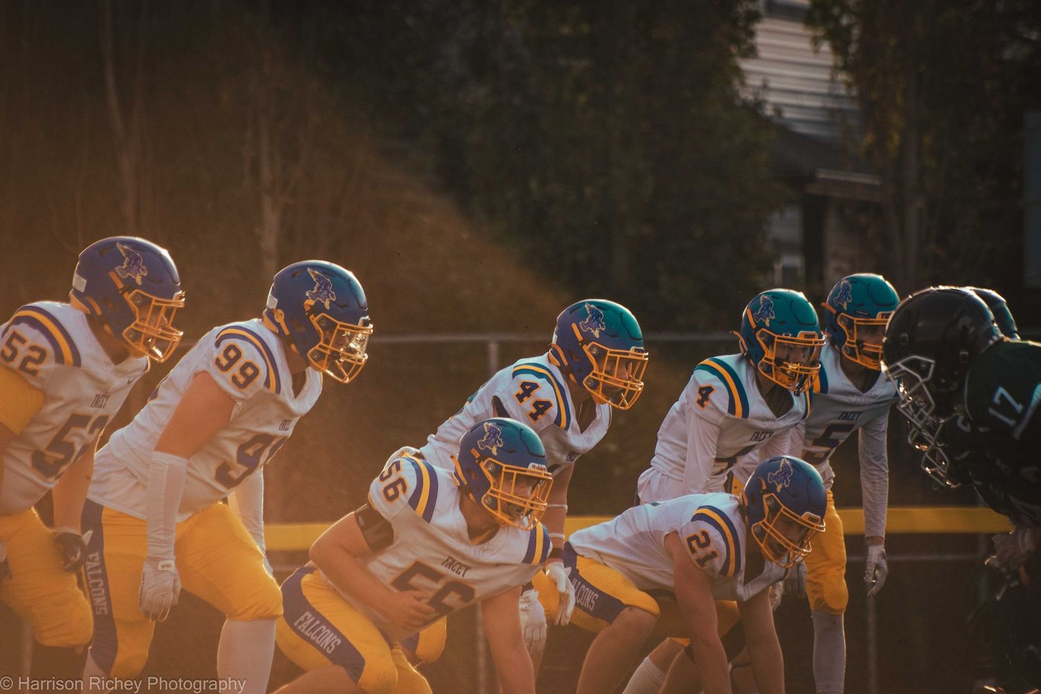 Football players line up in offensive formation during sunset game.
