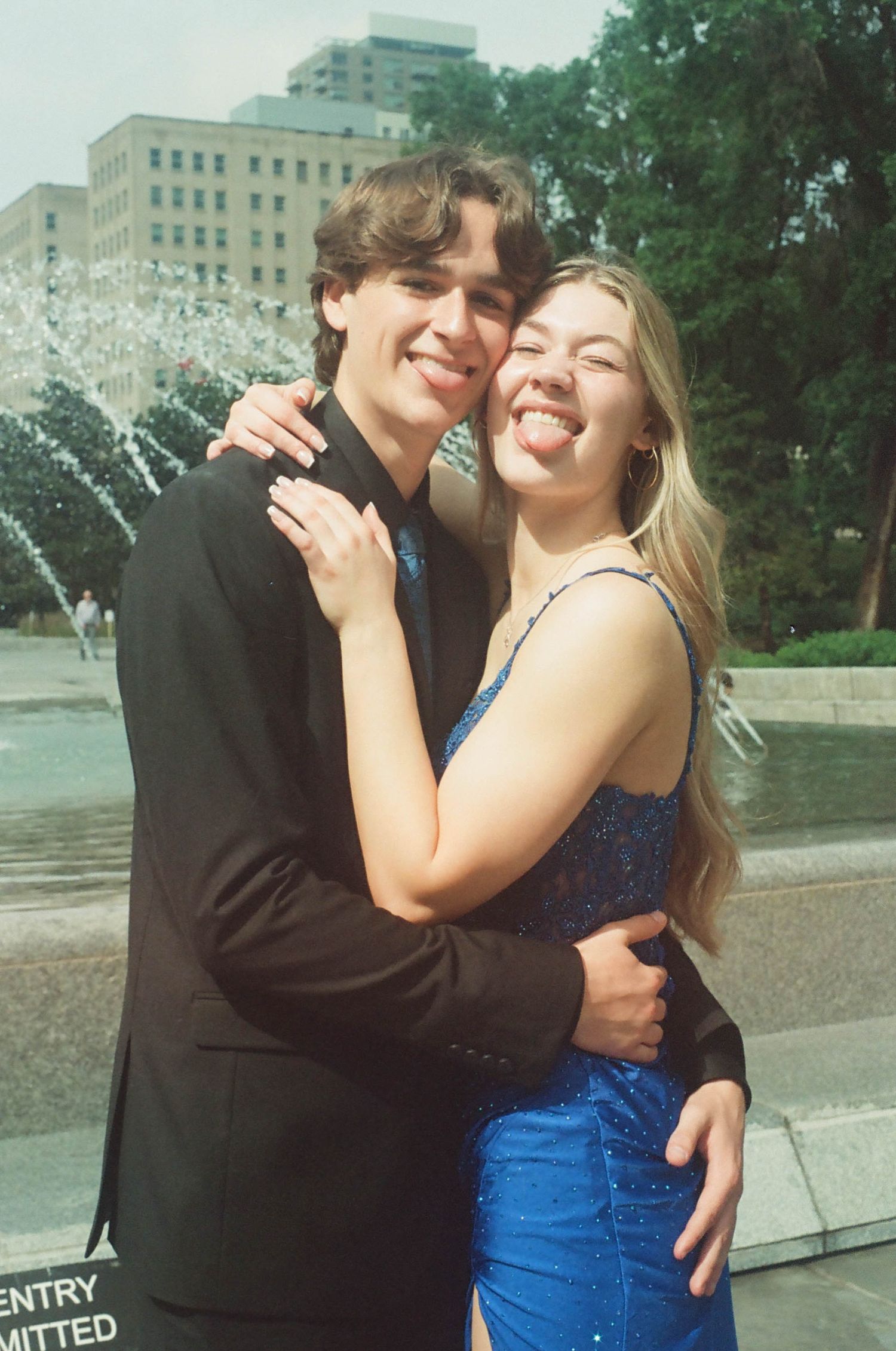 A couple in formal attire sharing an affectionate moment outside.