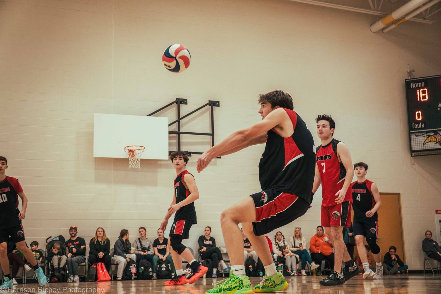 Athletes dive and jump to keep a volleyball in play during an indoor match.