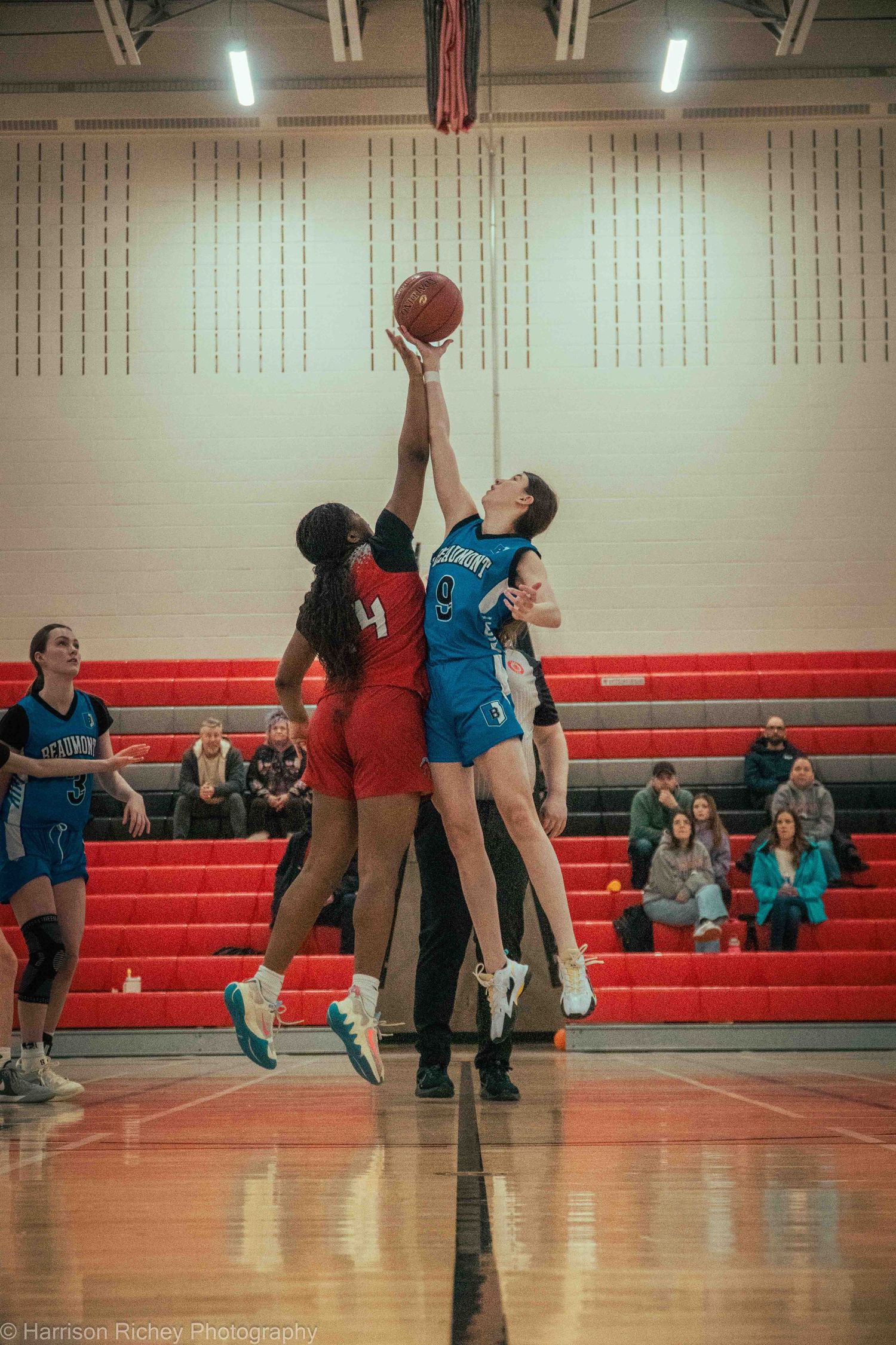 Youth basketball players in blue and white jerseys compete for the ball during an indoor game.