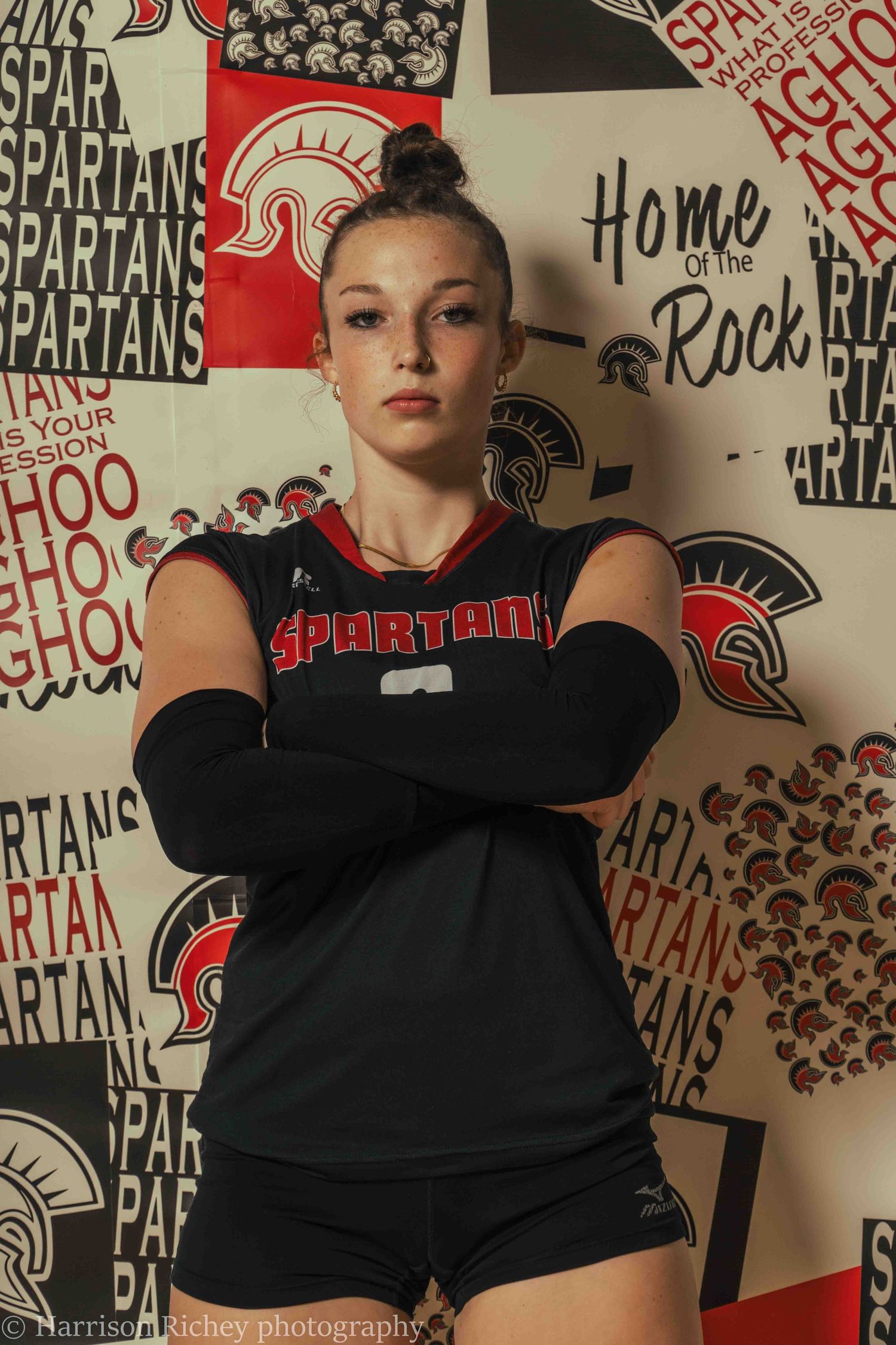Athletes in black uniforms pose confidently against logo-covered backdrop.