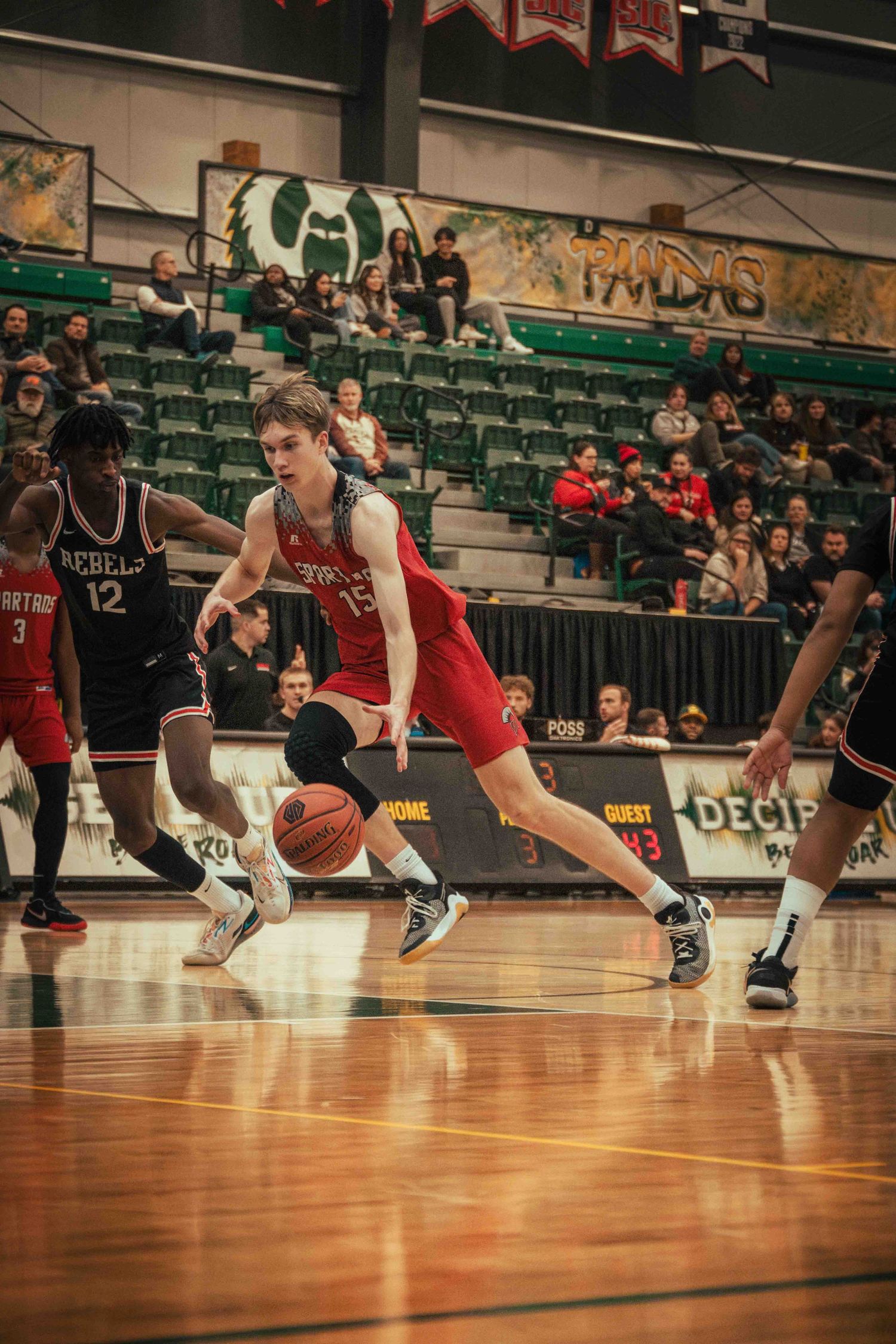 Basketball player drives to the hoop during competitive game action.