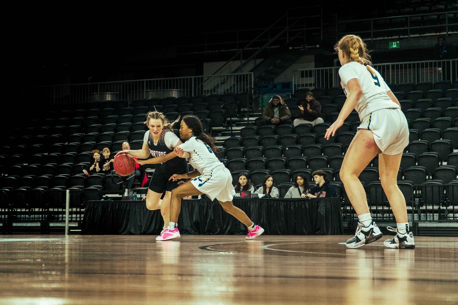 Players dive for a loose basketball during an intense defensive play.