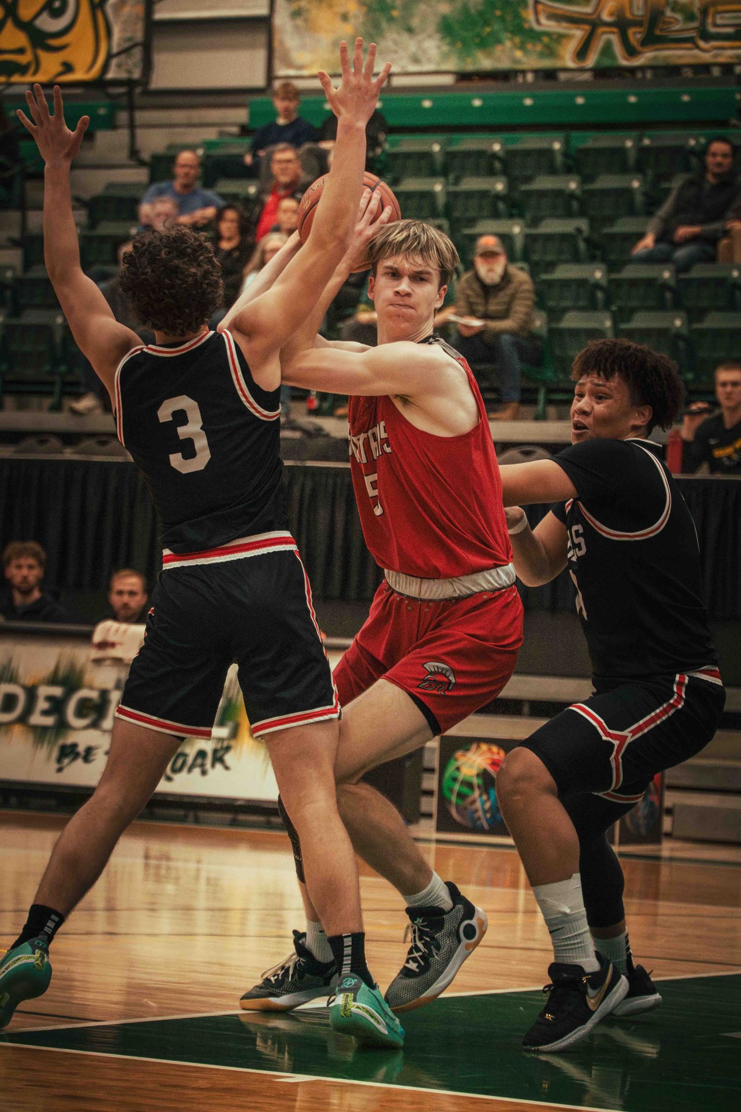 Basketball player attempts to score while defended by two opponents.