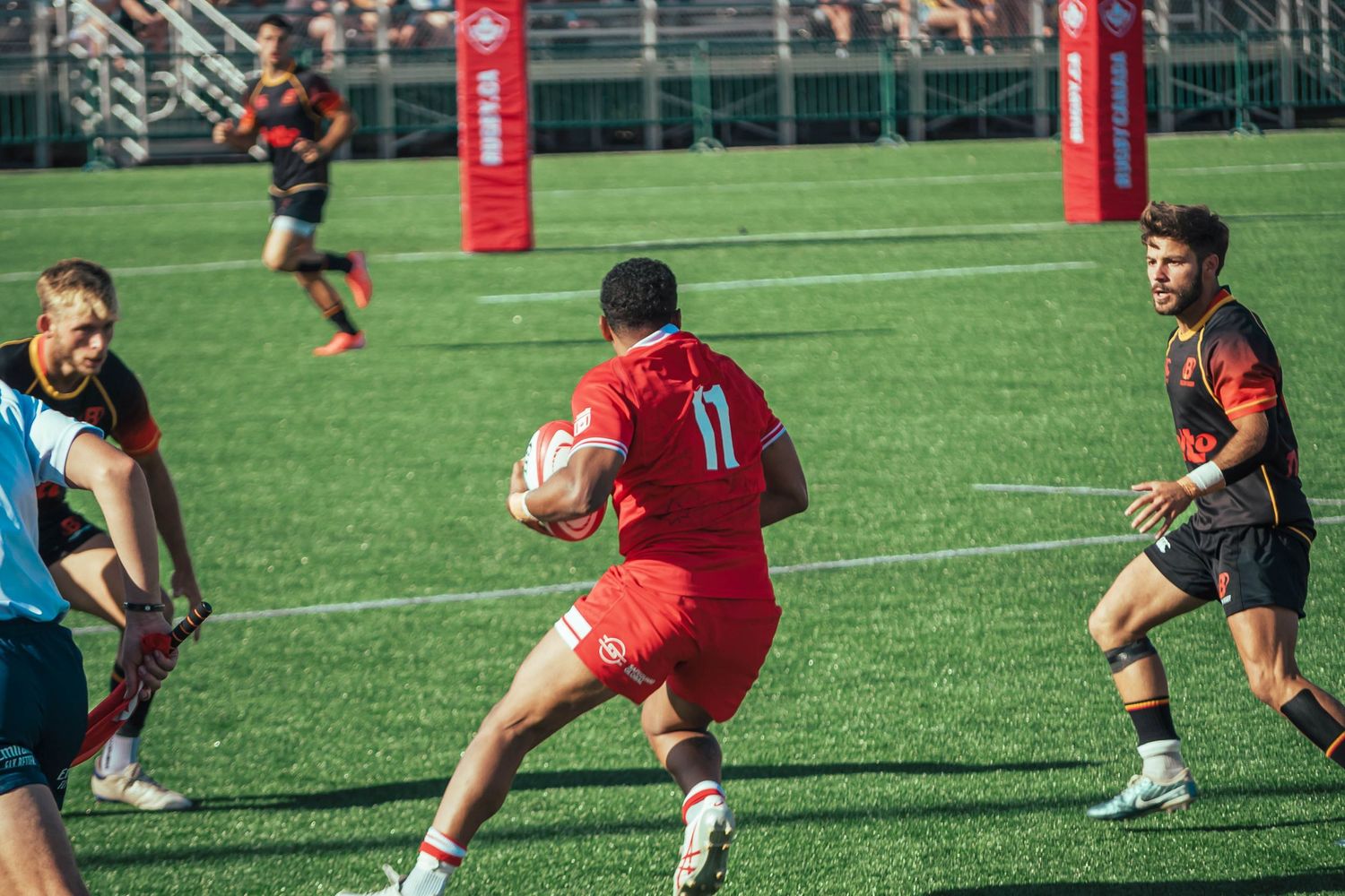 Rugby match action with players running and passing on a bright green field.