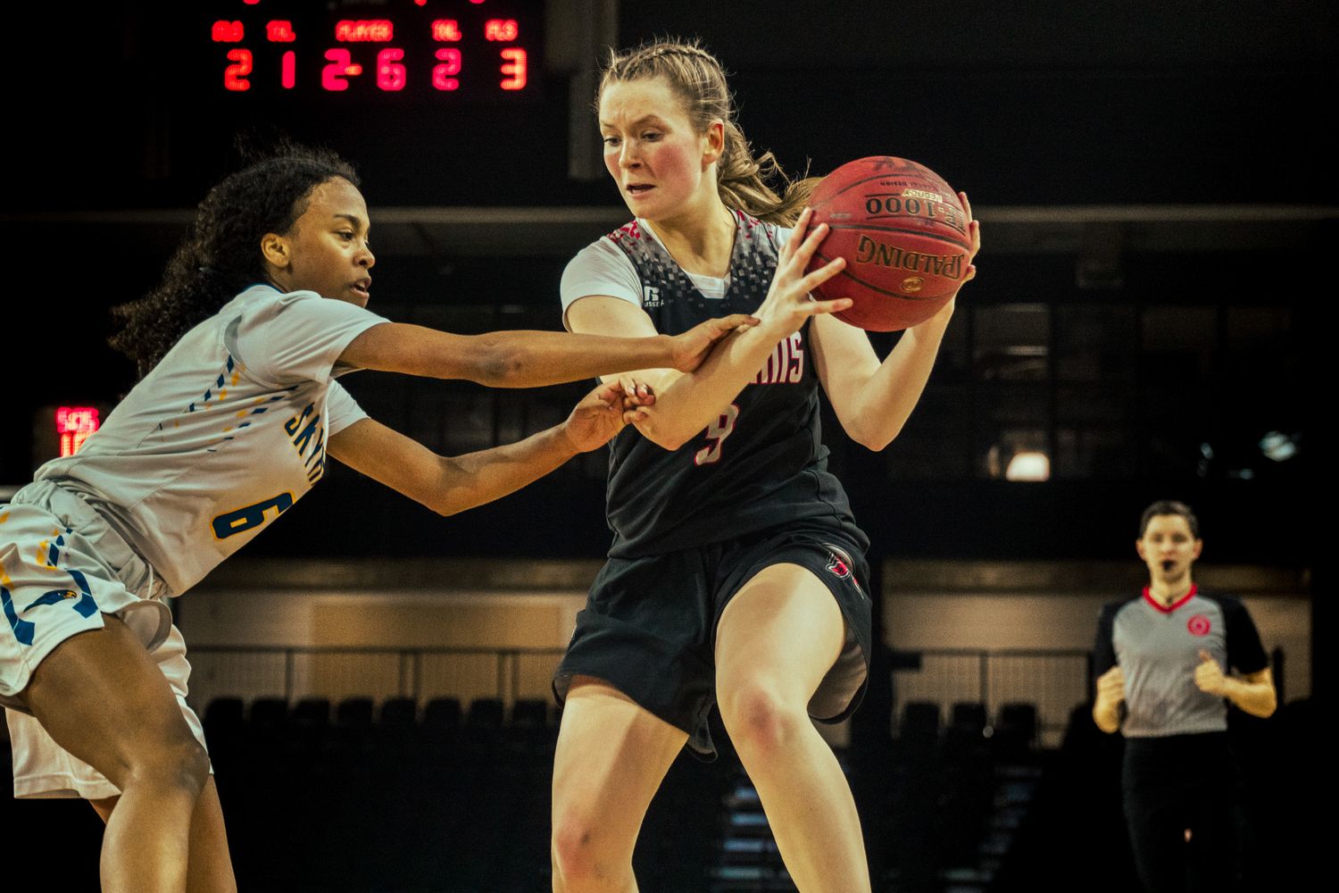 Intense basketball action as players compete for ball possession during competitive game.