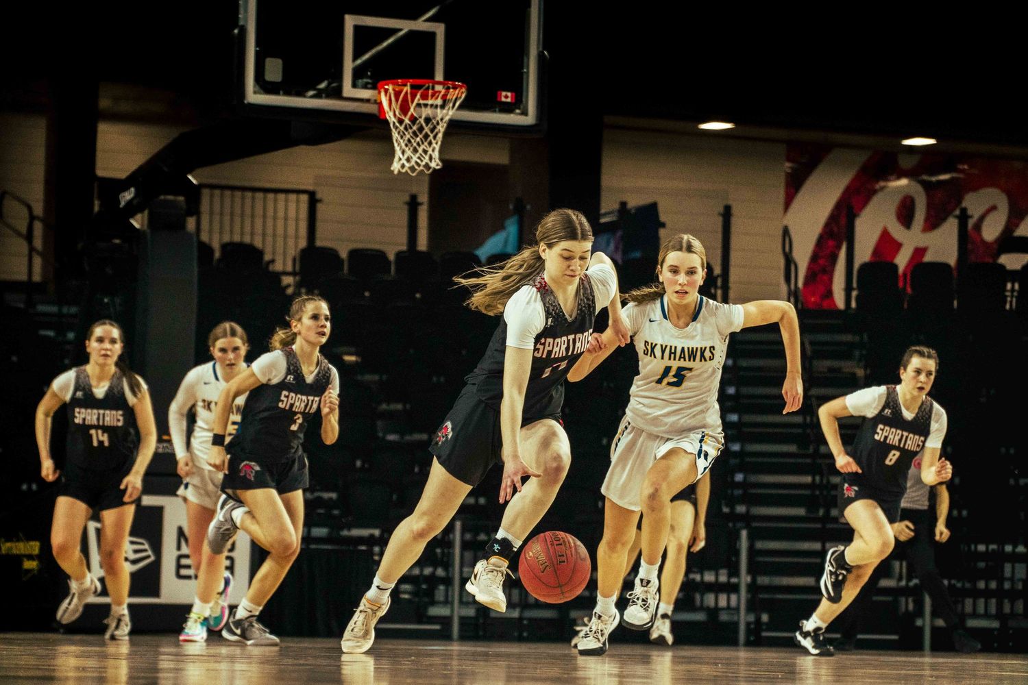 Basketball players sprint down the court during an intense game sequence.