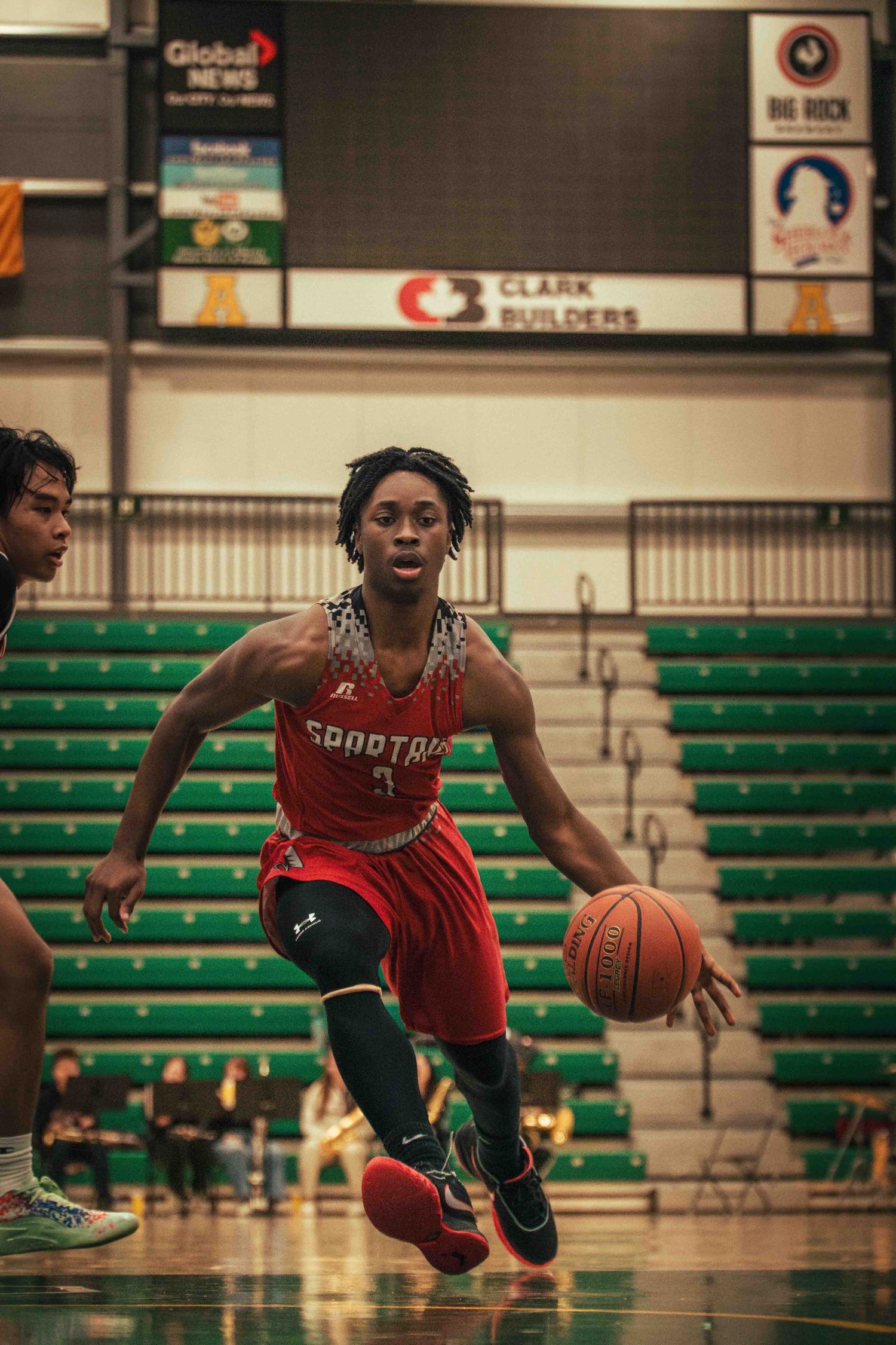 Basketball player in red uniform drives to the basket during competitive game.