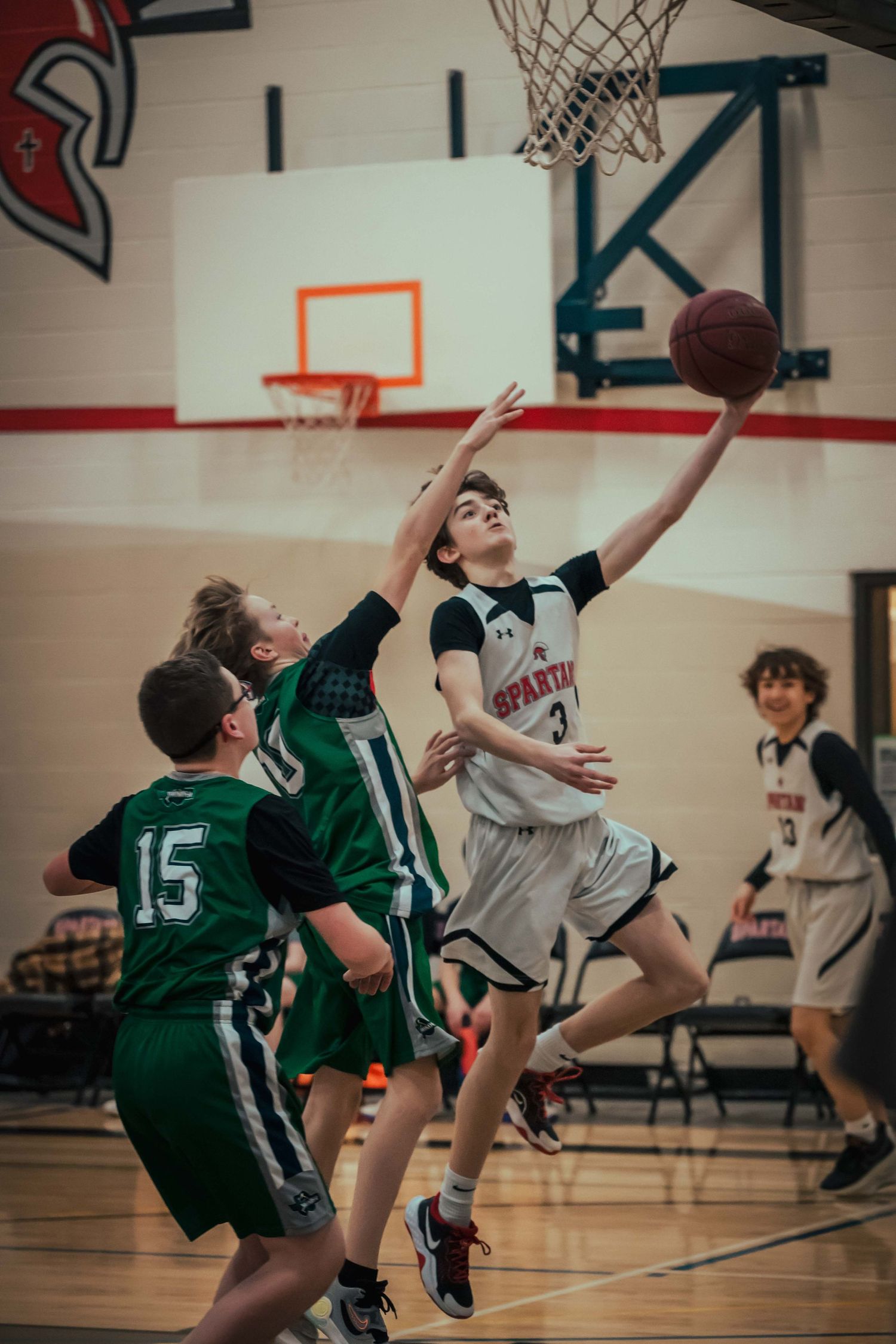 Two basketball teams compete intensely near the hoop during a youth league game.