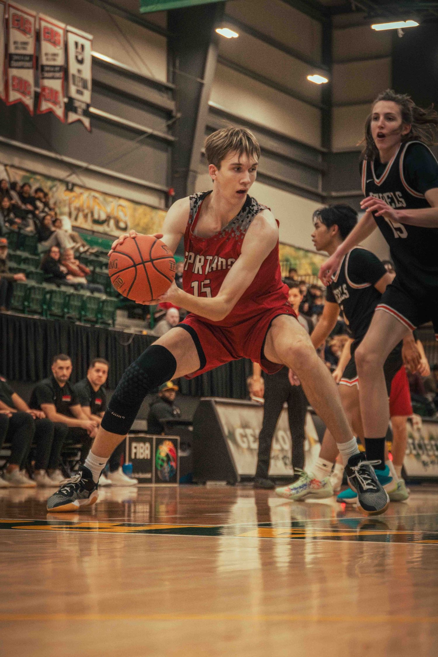 Basketball player makes aggressive move while handling ball during game.