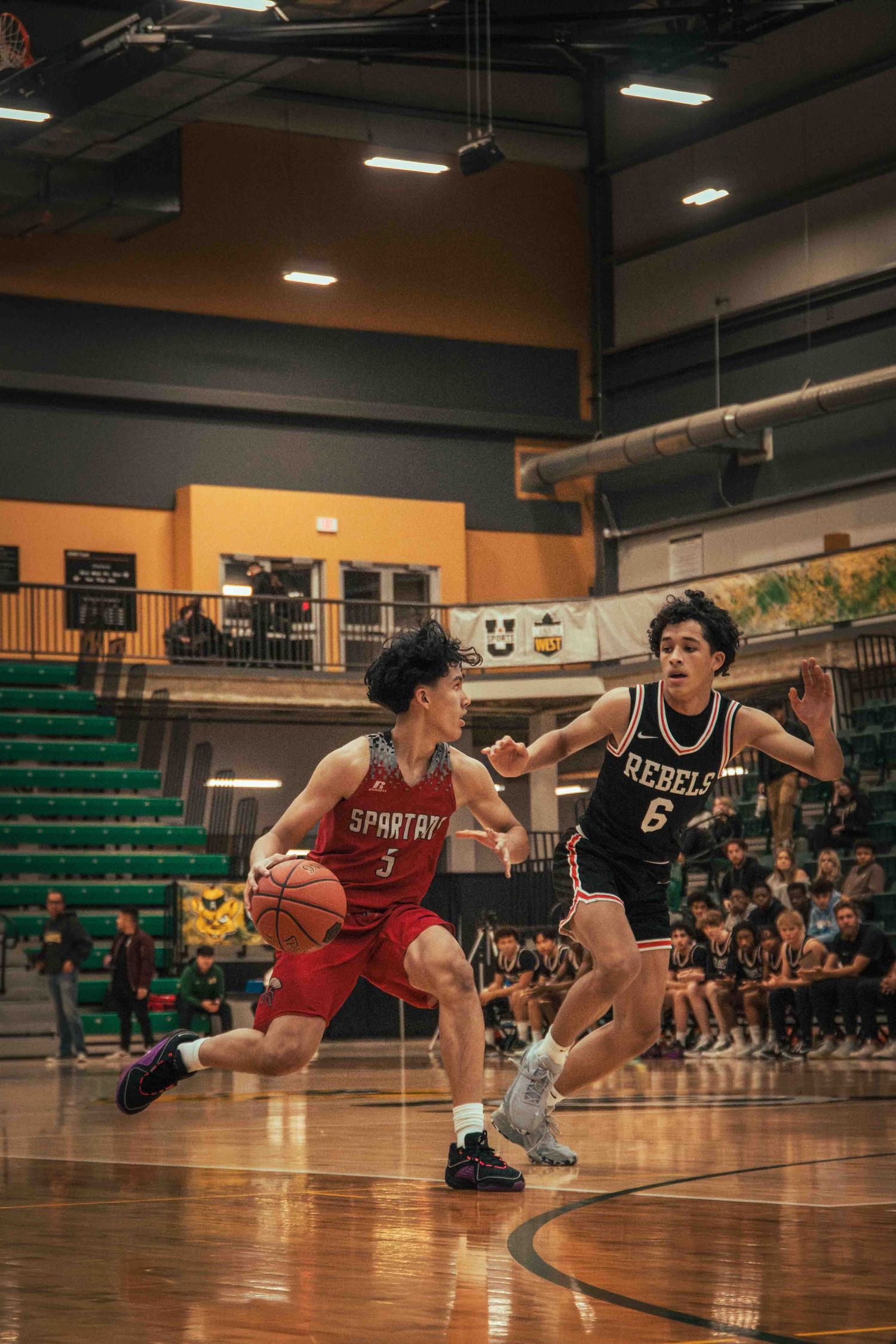 Basketball players battle for position during competitive game in gymnasium.