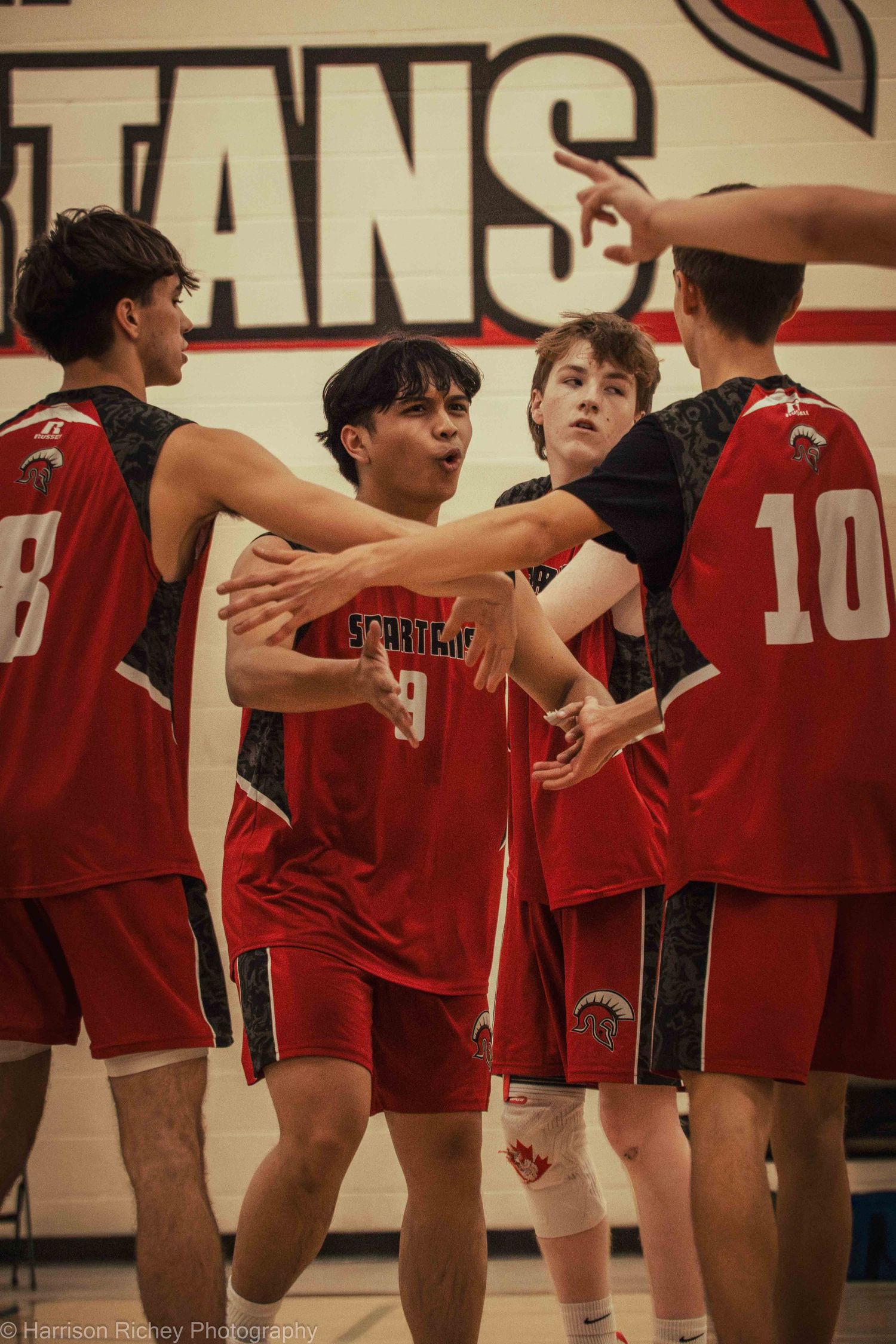Team members in red jerseys line up along the basketball court during a game.