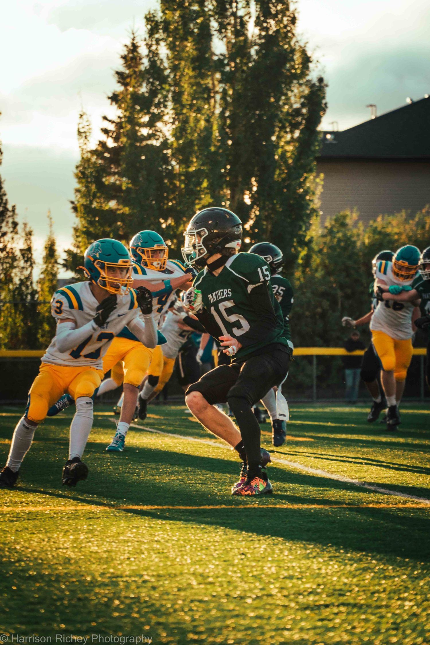 Football players clash during a sunset game with dramatic lighting on the field.