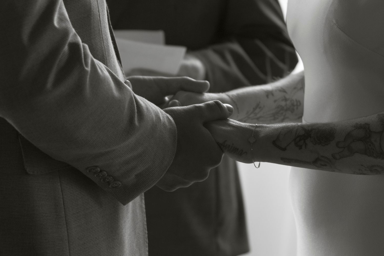 A black and white close-up photo of hands exchanging rings during a wedding ceremony.