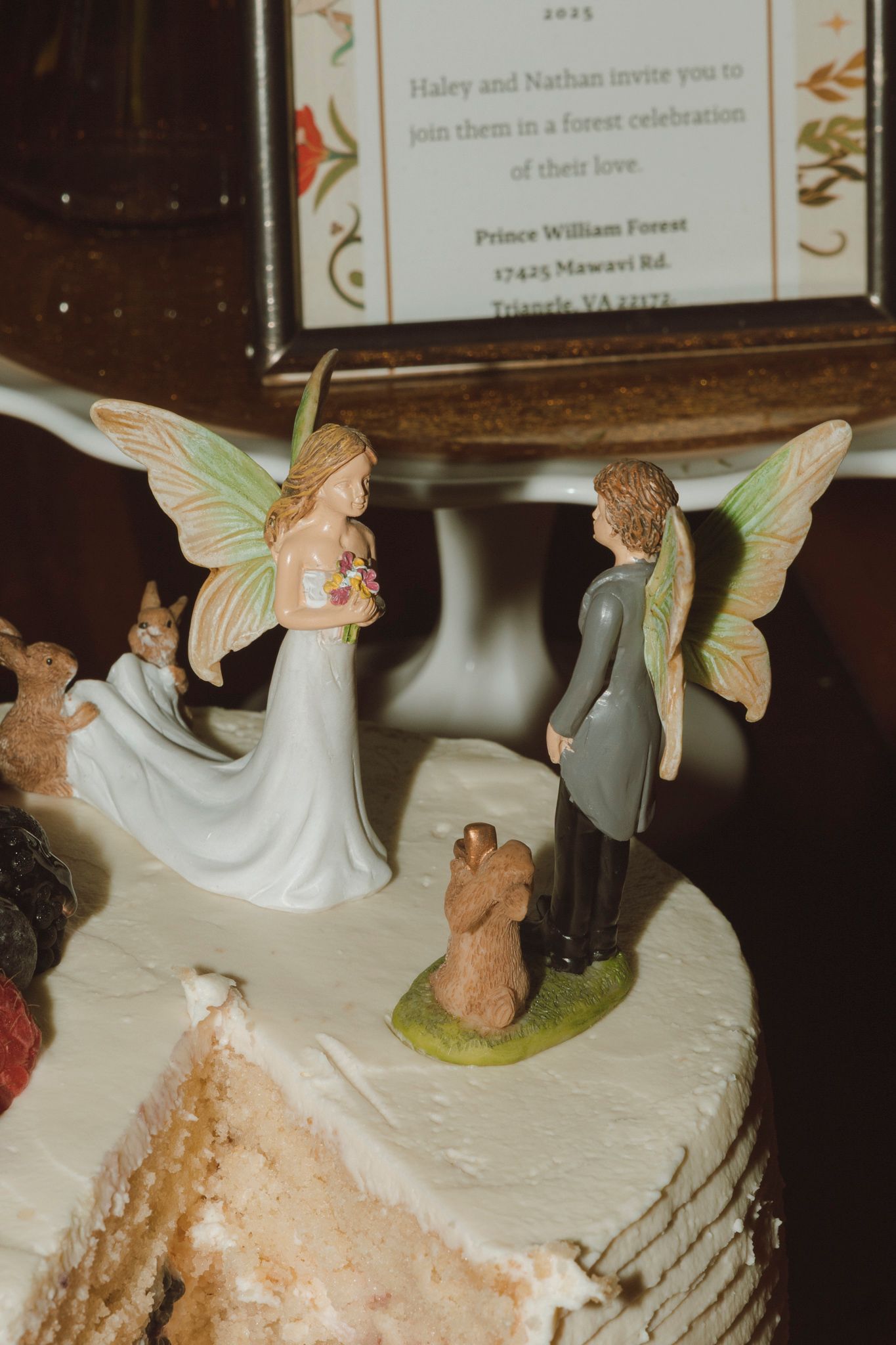 A vintage wedding cake topper with cherub angels decorating a partially eaten white frosted cake.