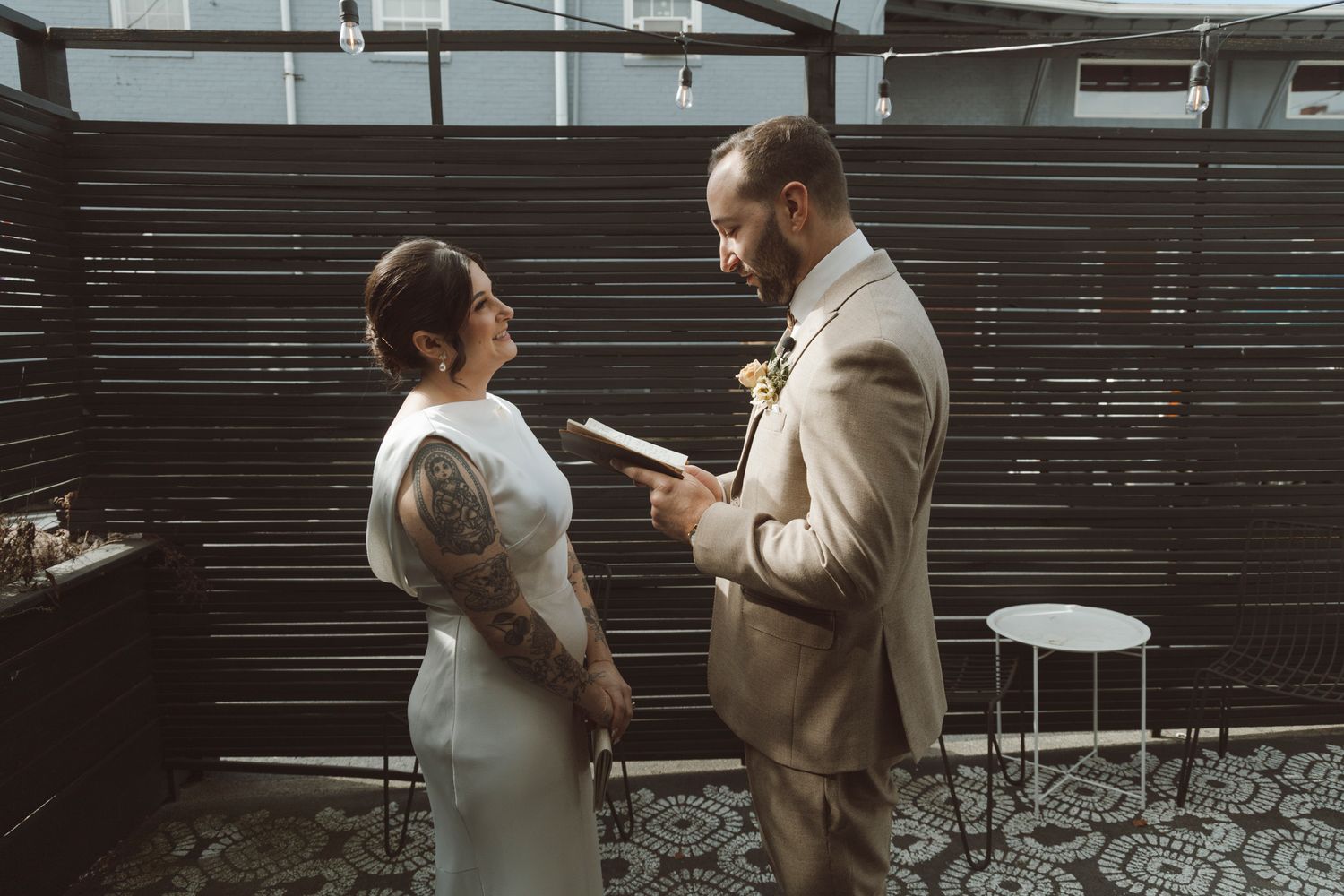 A couple exchanges vows in front of a modern slatted wall during their wedding ceremony.