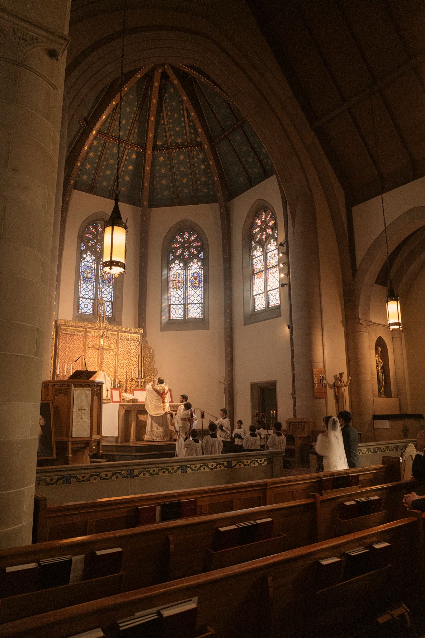 Wedding ceremony at church altar beneath octagonal dome with stained glass windows.