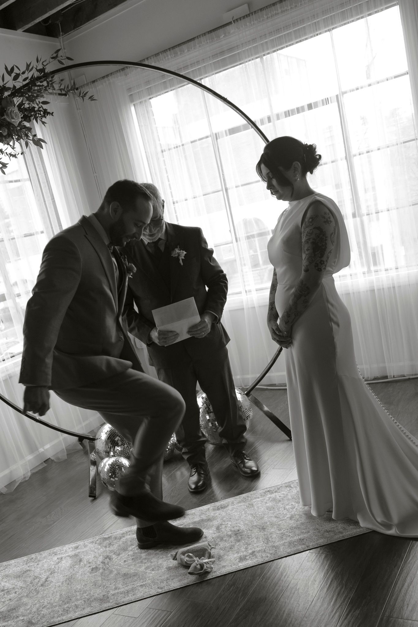 Black and white sequence showing people preparing and putting on shoes in a room with bright windows.