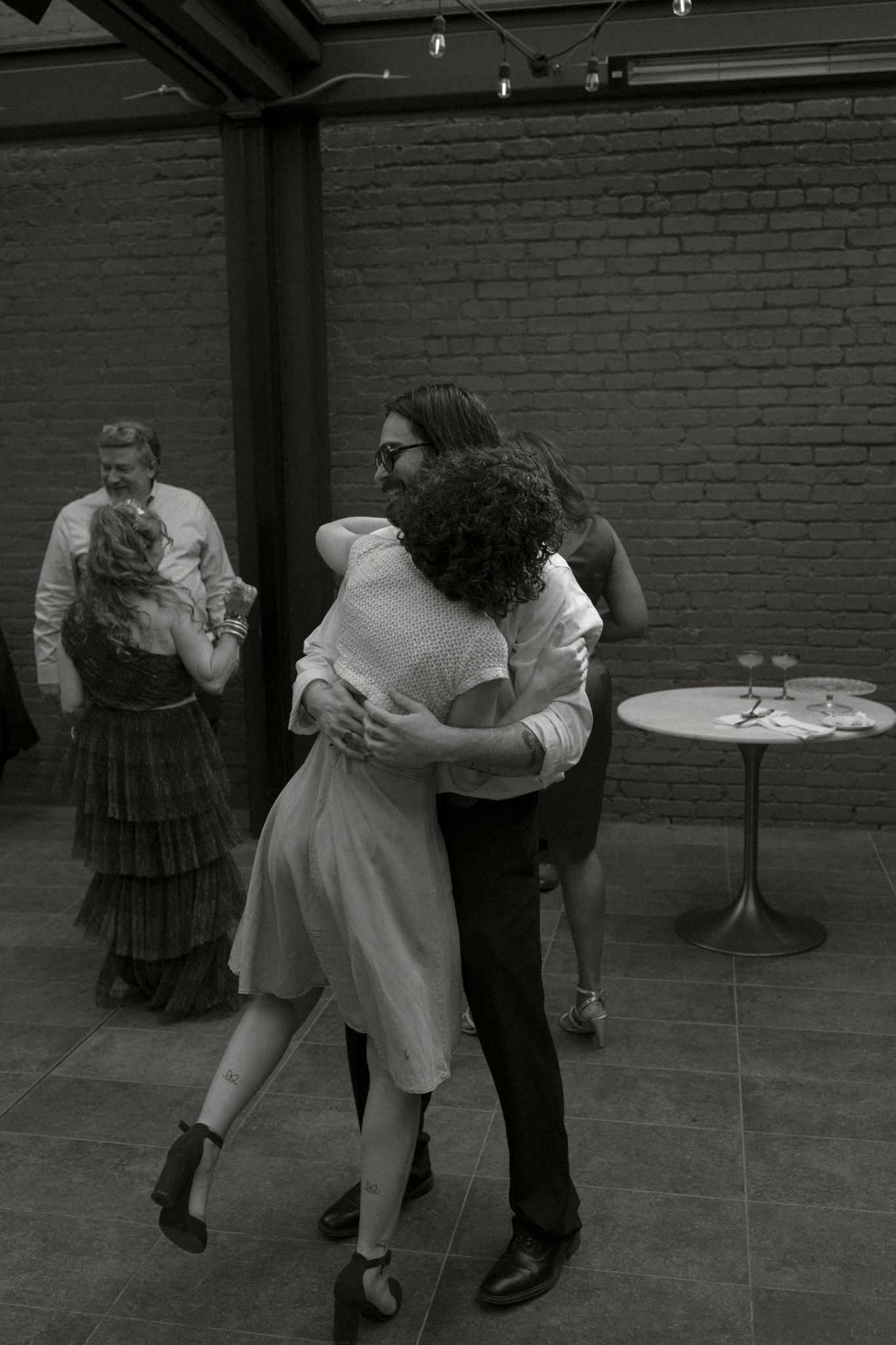 A black and white sequence showing a couple dancing together in a brick-walled room with dramatic dips and movements.