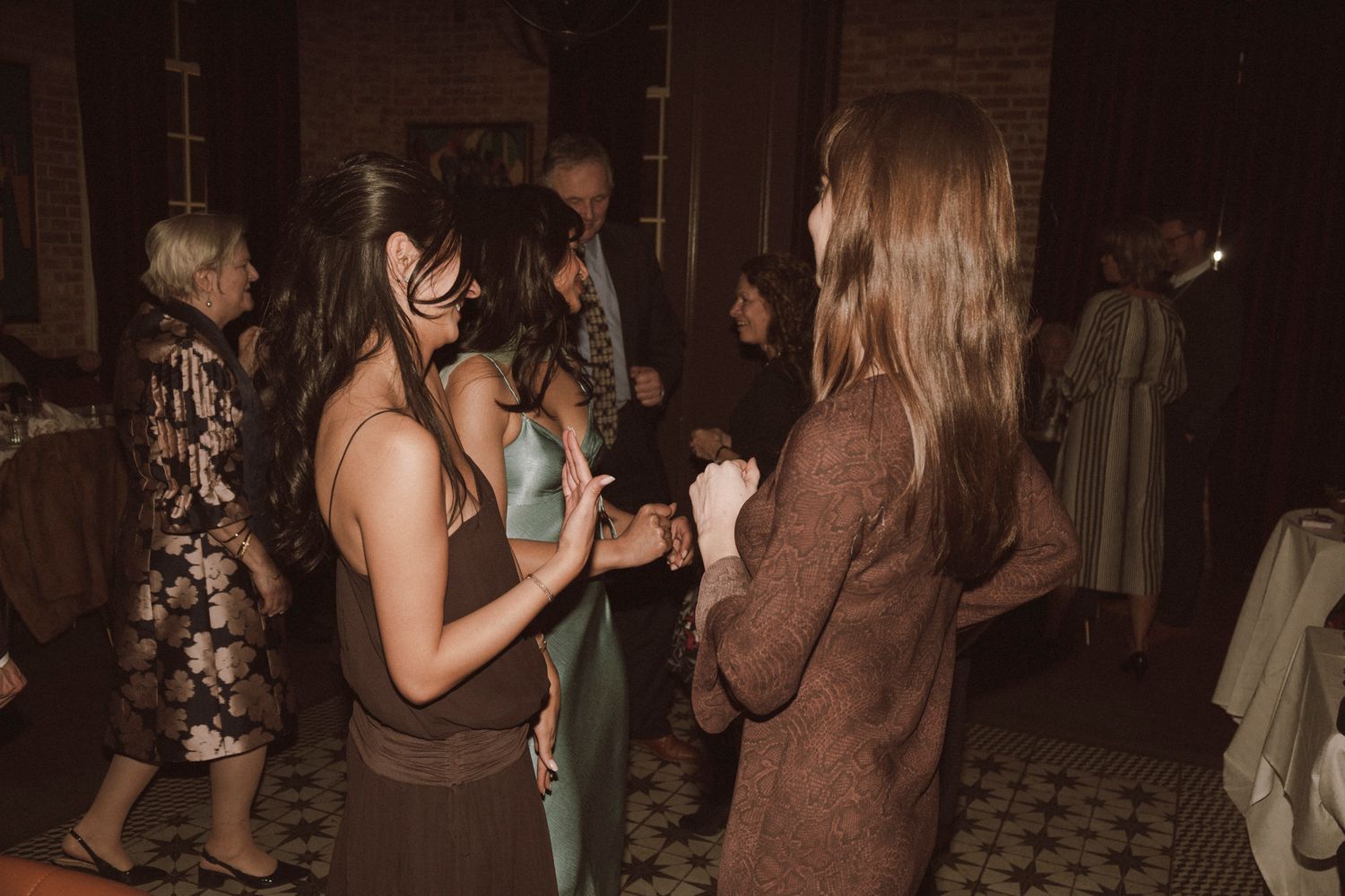 Guests mingle and socialize in warmly lit venue with brick walls during an evening wedding reception.
