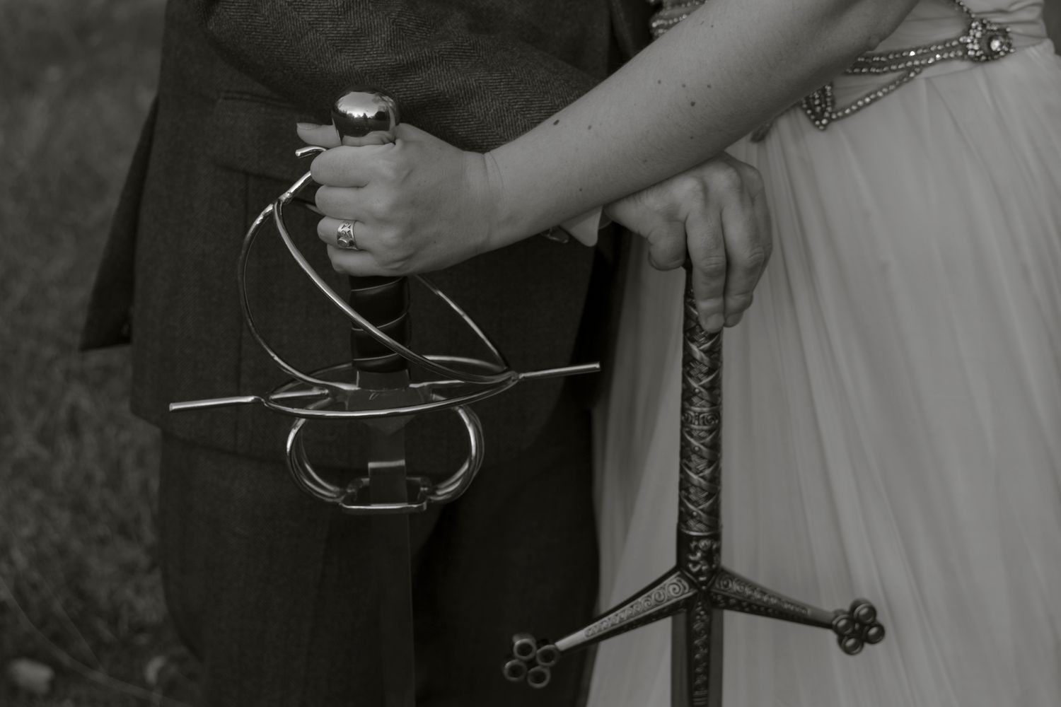 A bride and groom cut their wedding cake together while holding the knife with both their hands.