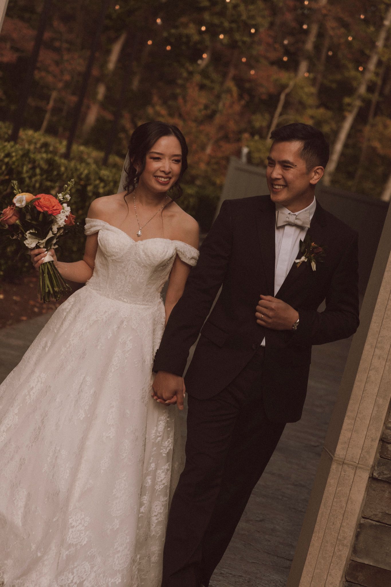 A couple shares a romantic moment during their wedding celebration with string lights glowing in the background.
