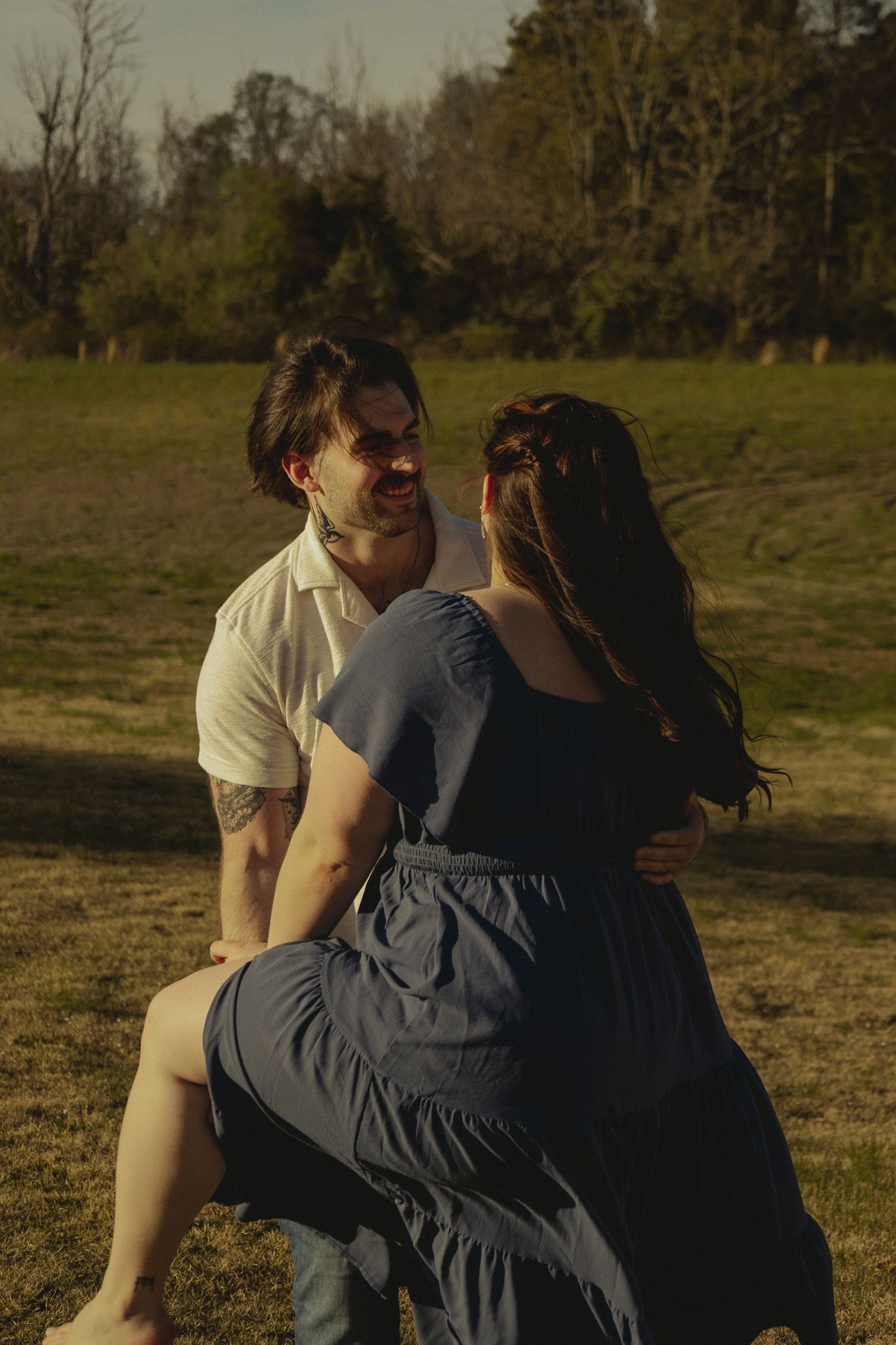 Smiling man and woman sharing a joyful moment together in a grassy field.
